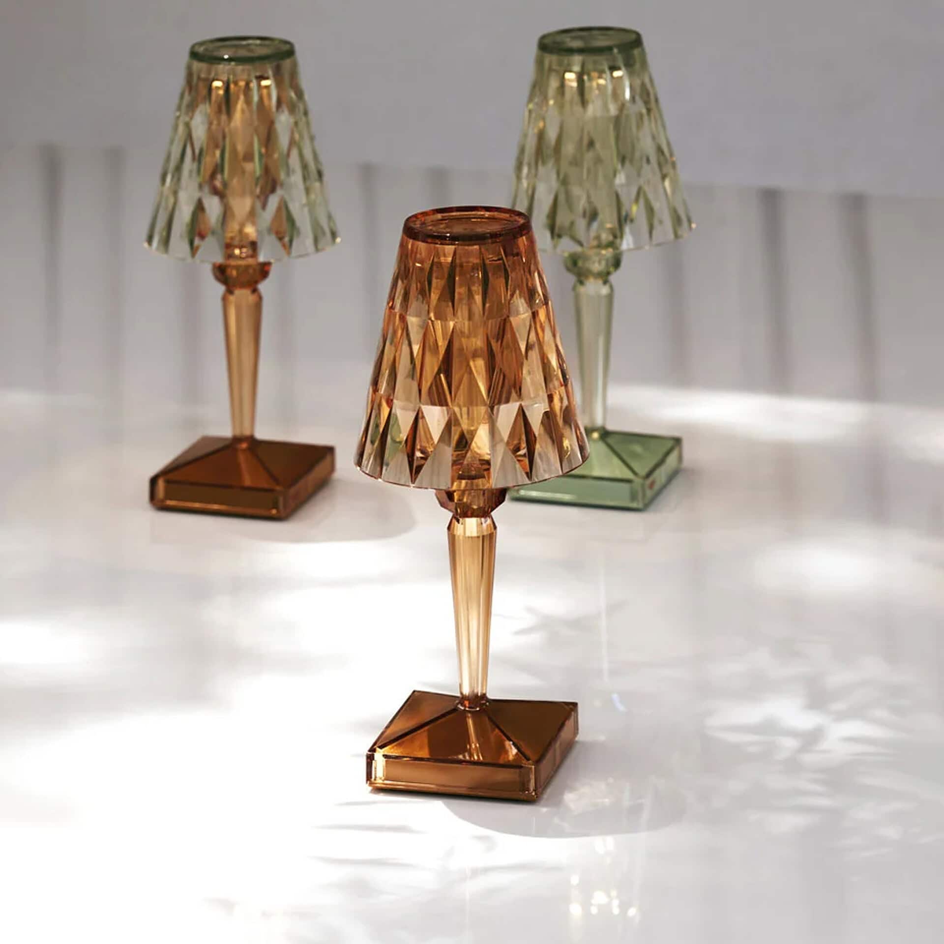 Stylish glass table lamps with geometric faceted design in bronze and green finishes.