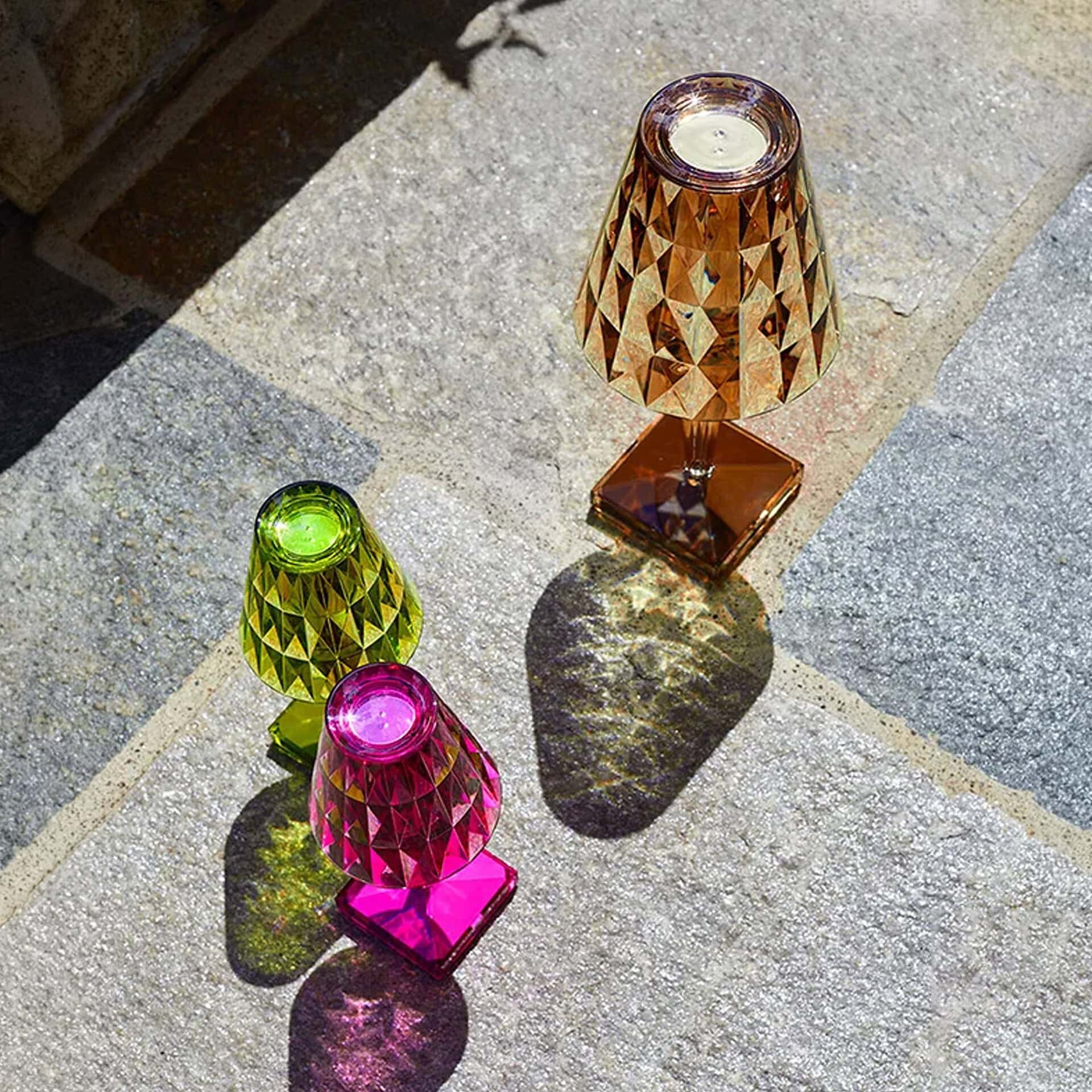 Colorful geometric glass candle holders on stone surface.
