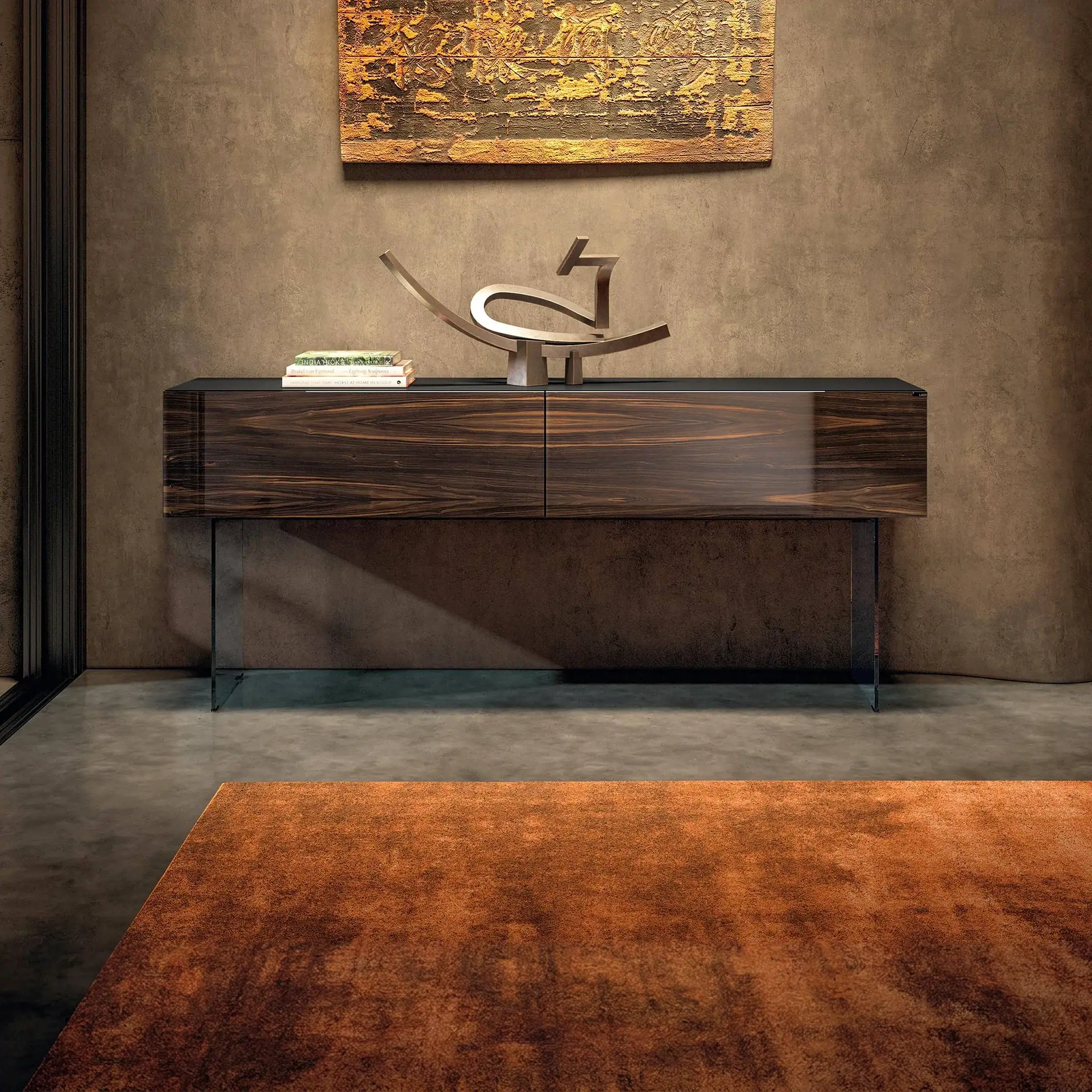 A modern living space with a dark wood console table, abstract metallic sculpture, and a rust-colored rug on a concrete floor.