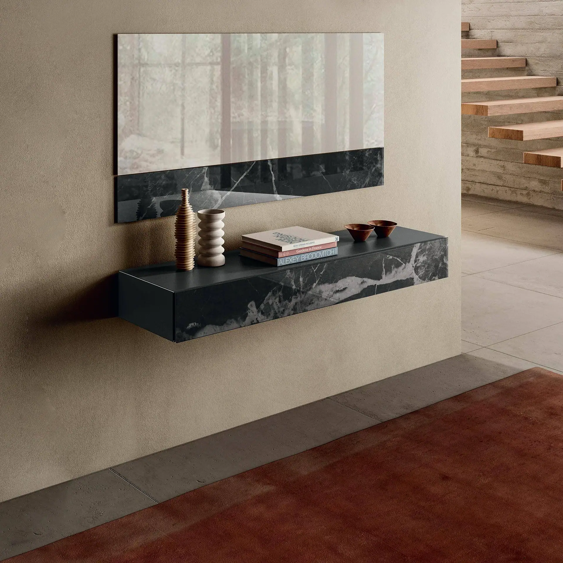 A modern floating console with a mirror and shelf, both featuring a black marble pattern, against a beige wall. The shelf holds vases, books, and bowls. A wooden staircase and a red rug are visible in the background.