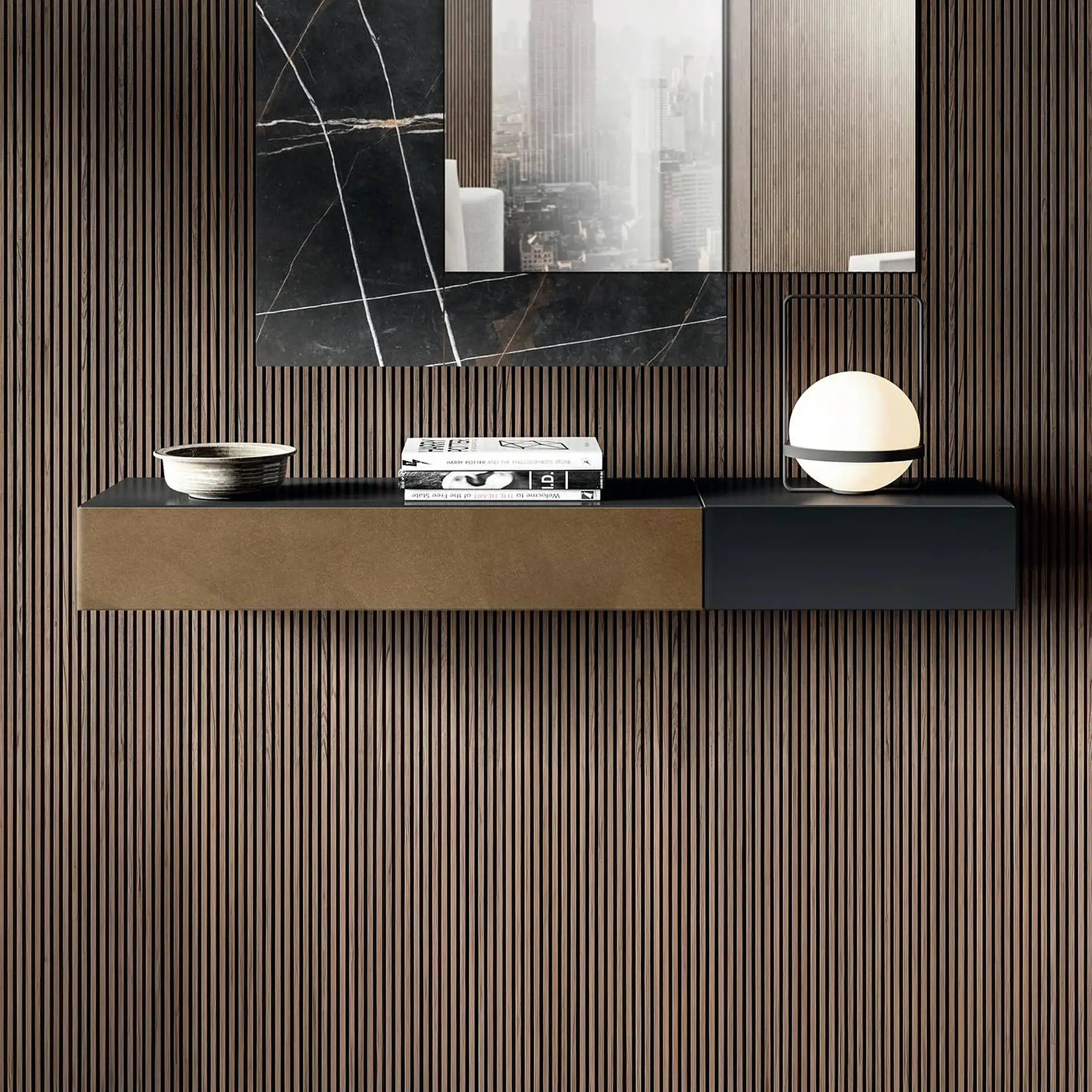 A floating two-toned console shelf against a dark slatted wood wall. On the shelf are a ceramic bowl, books, and a spherical lamp. Above it, a mirror reflects a cityscape with a black marble accent.