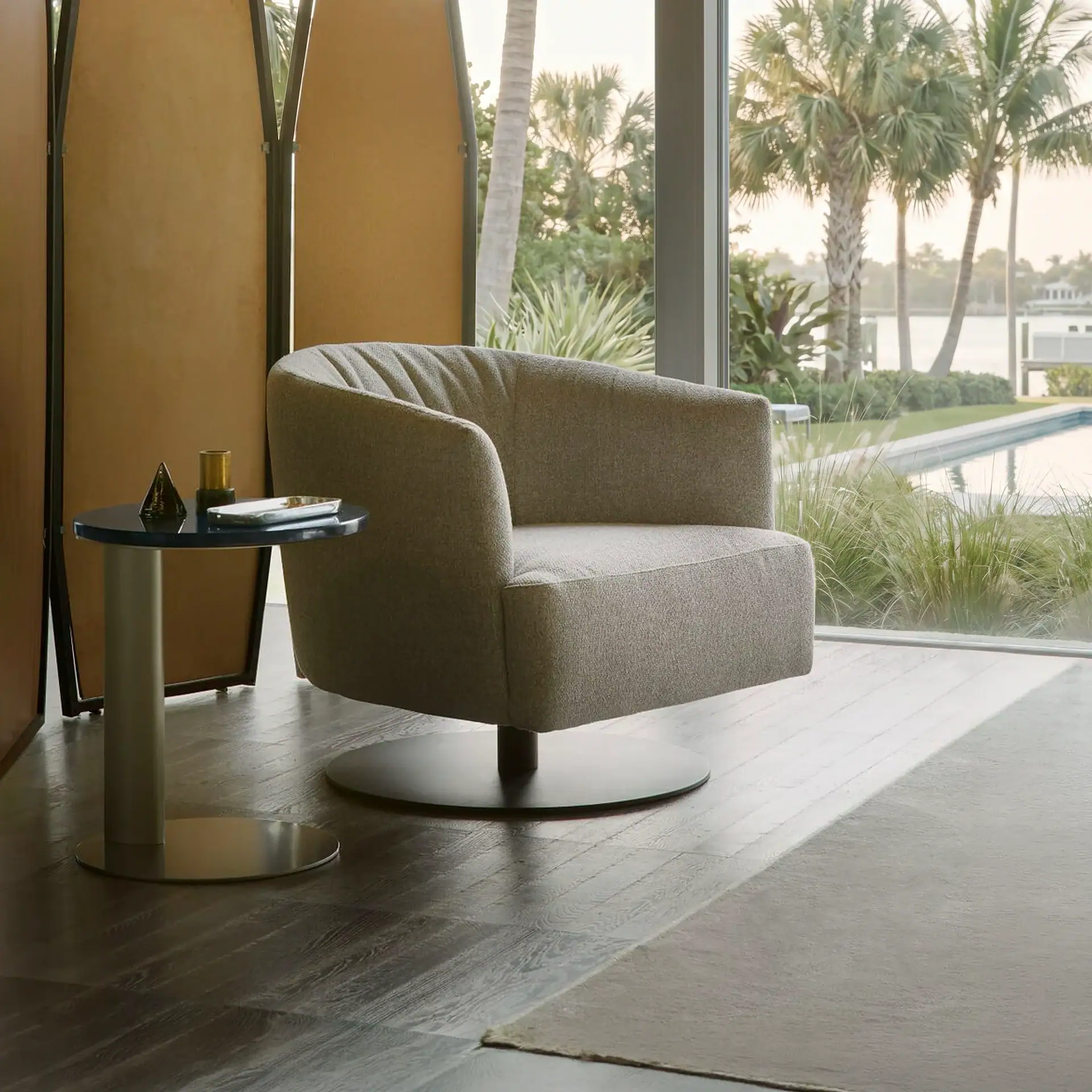 Modern lounge chair in a stylish interior with large windows overlooking a water landscape.