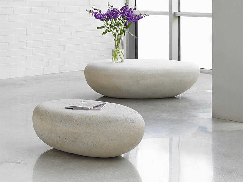 Contemporary concrete tables with smooth, rounded design in minimalist interior setting.