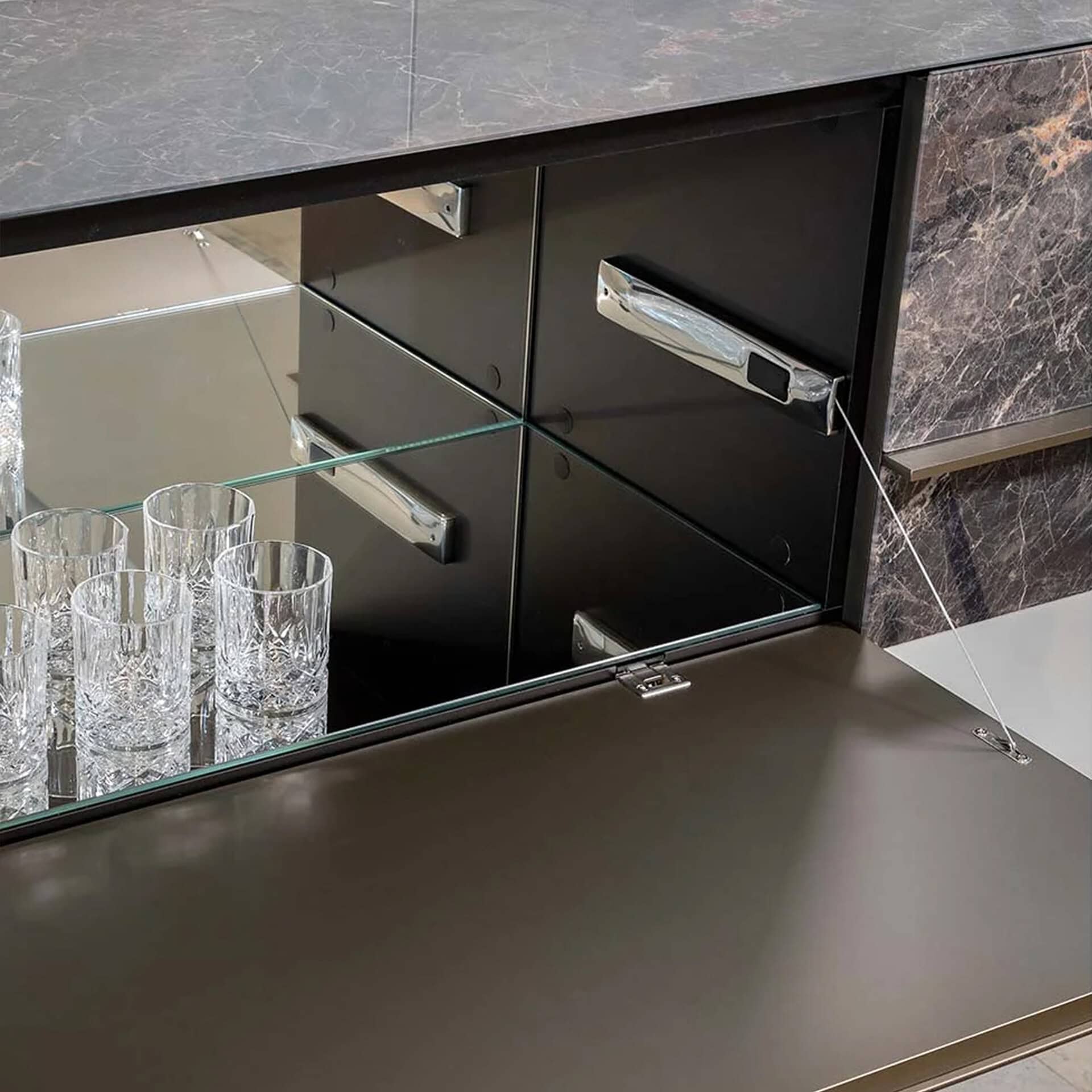 Modern black bar cabinet with glassware and mirrored doors.