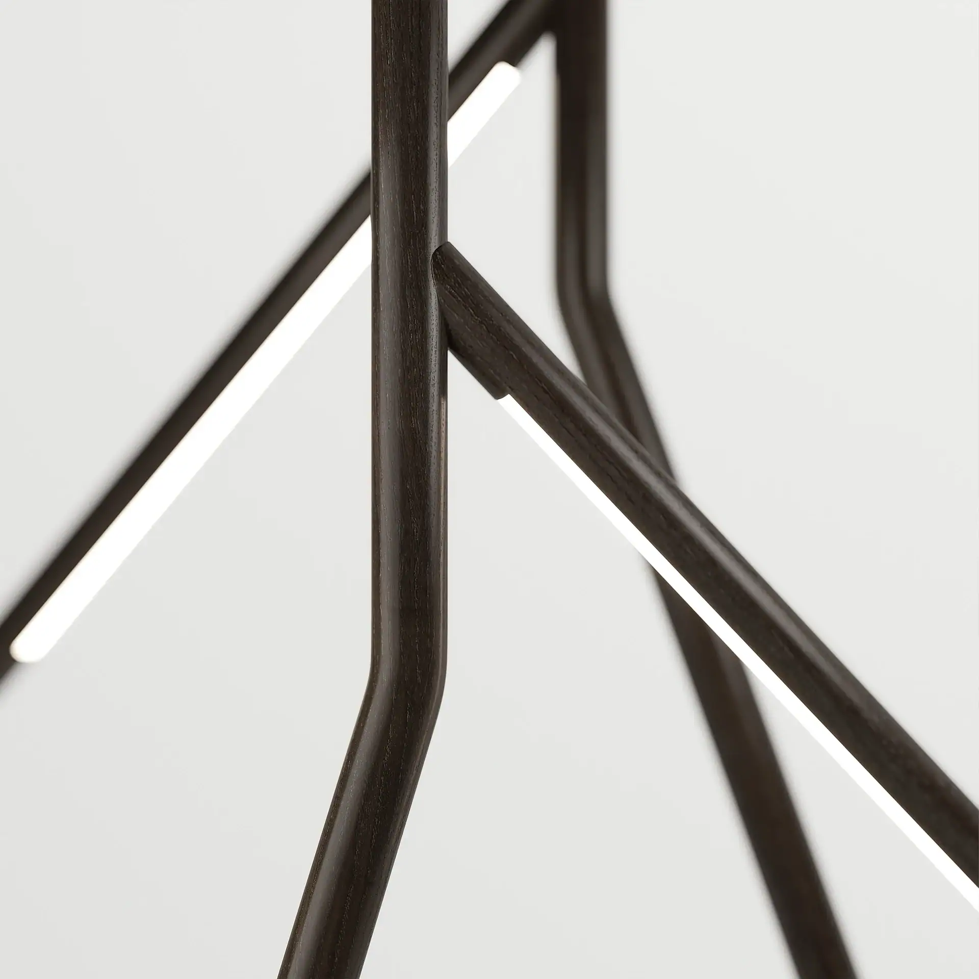 Close-up of a modern lighting fixture with dark brown, textured rods and integrated bright white LED strips against a white background.