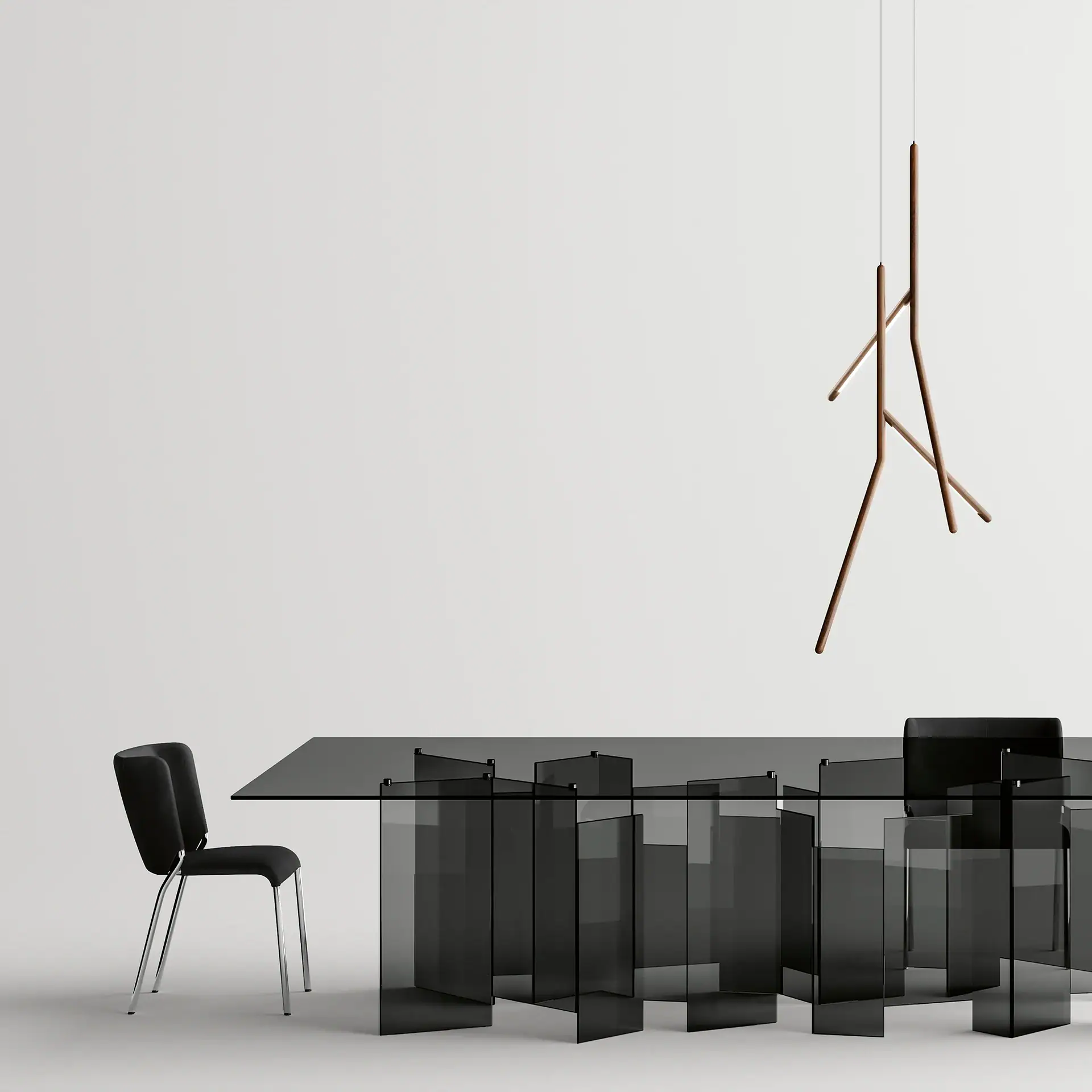 A minimalist dining room with a dark glass table, black chairs, and a unique brown branch-like pendant light against a light grey background.