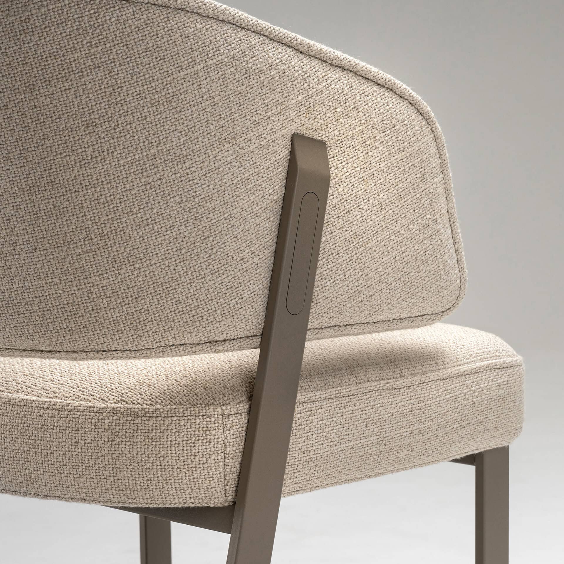 Modern beige upholstered chair with sleek metal leg detail.
