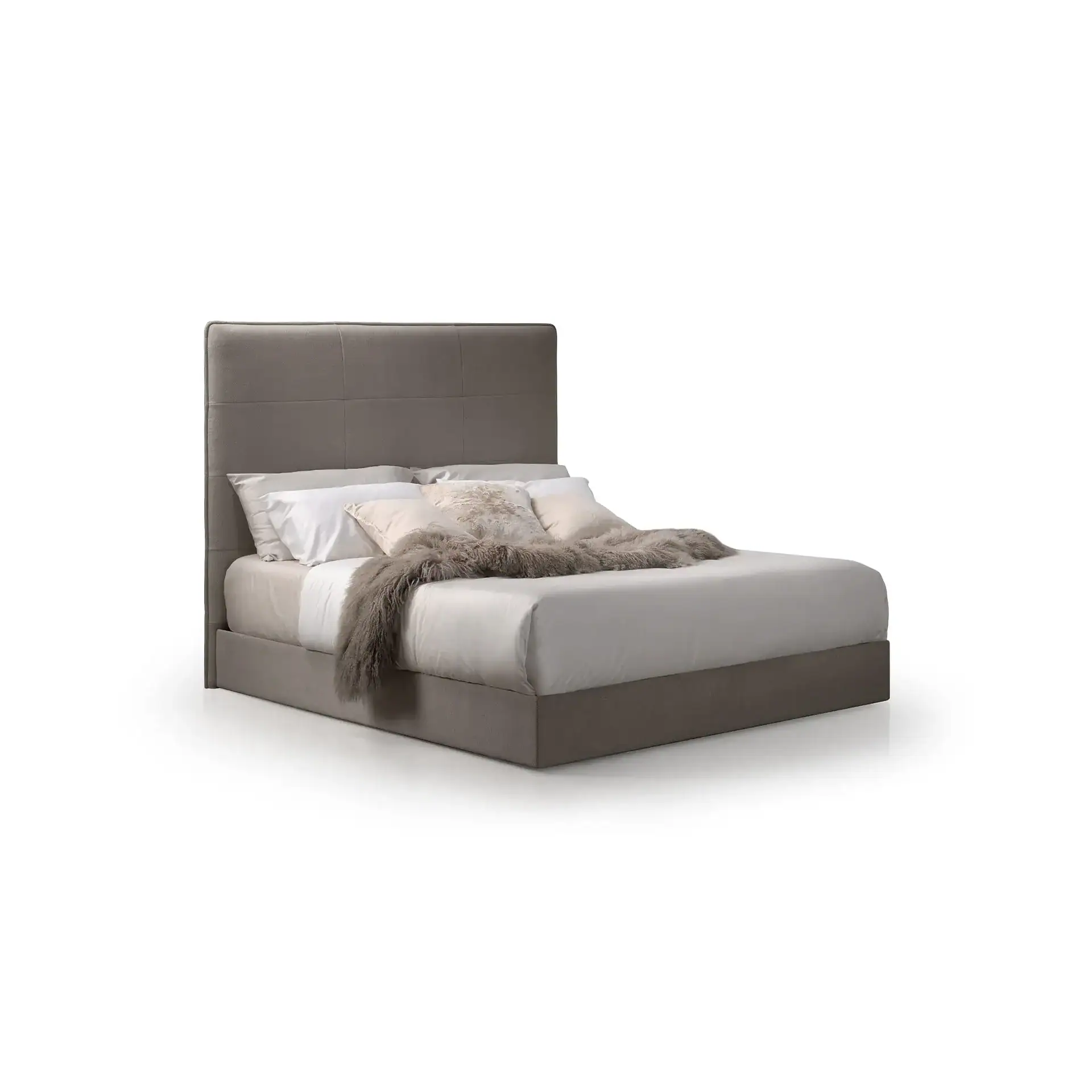 A gray upholstered bed with a tall headboard, white sheets, decorative pillows, and a gray faux fur throw blanket.