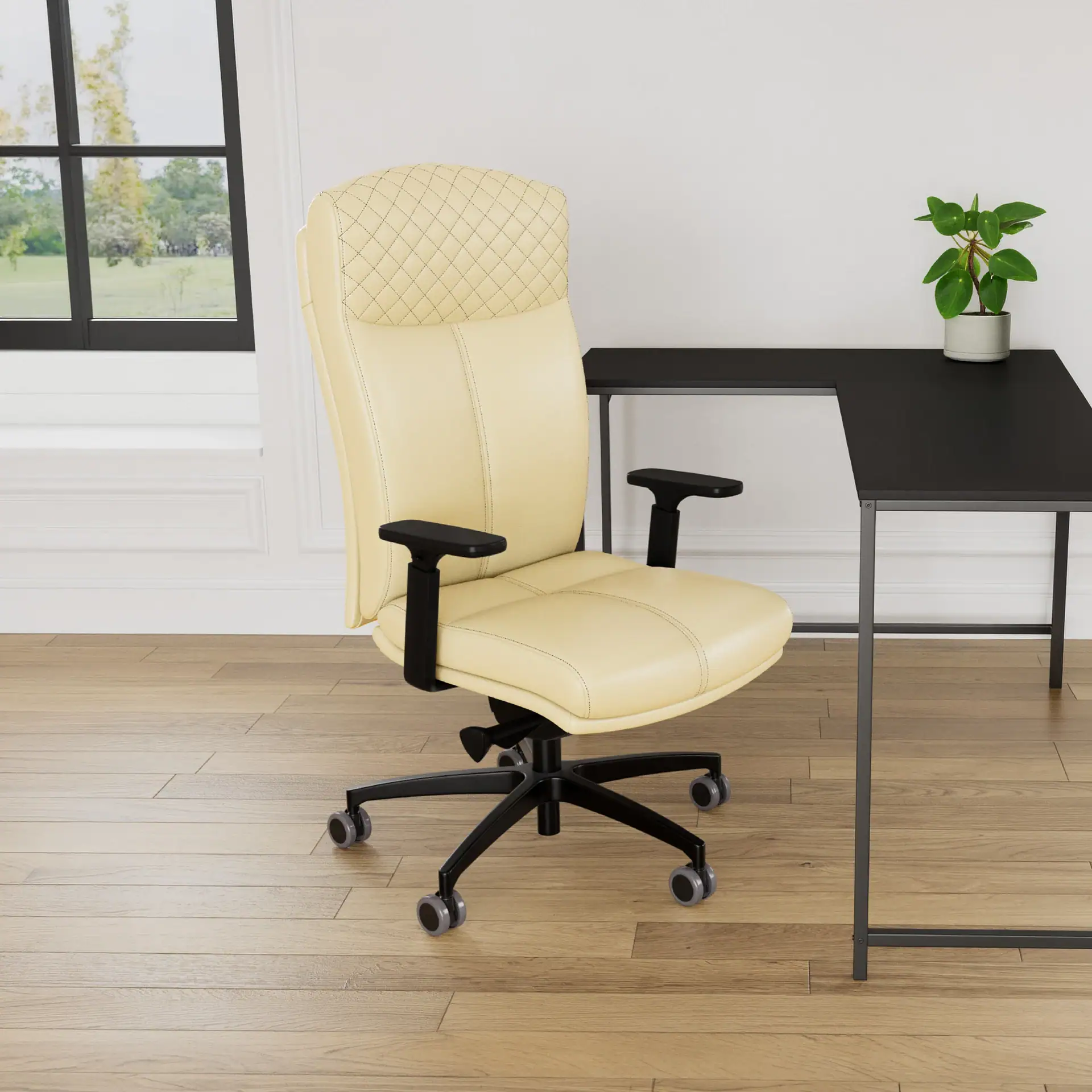 Cream ergonomic office chair with quilted headrest next to a black L-shaped desk with a potted plant, in a room with wood flooring and a large window.