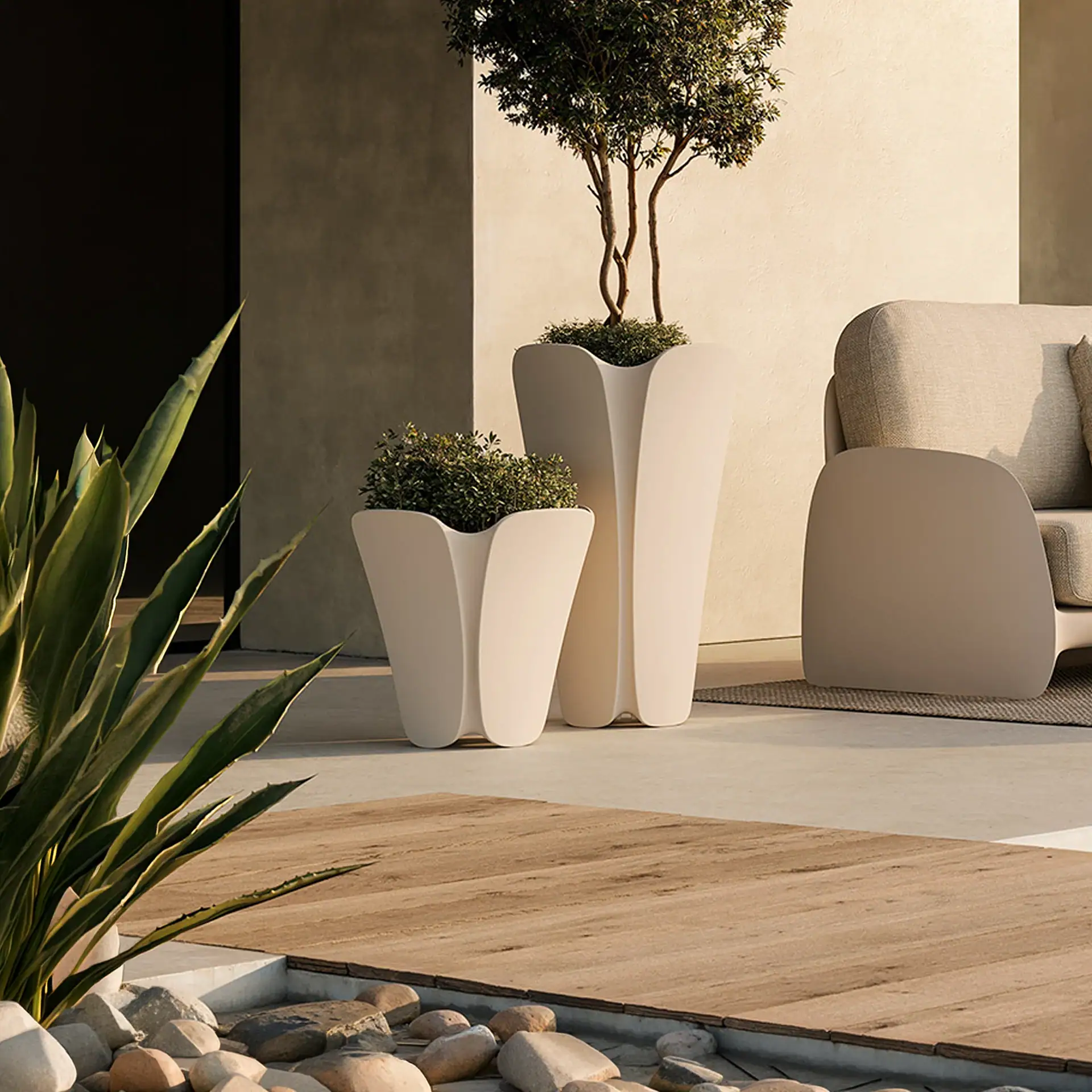 Two modern, light-colored planters with green plants on a patio with a sofa and wooden decking.