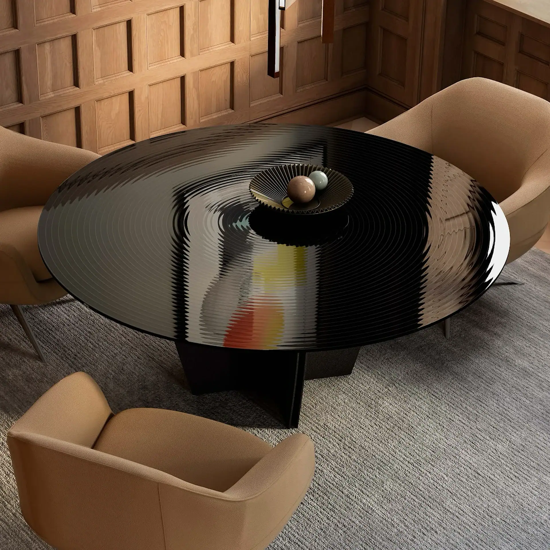 A high-angle view of a modern dining space with a round black table featuring a rippled, reflective surface. Three tan upholstered chairs surround the table, which sits on a gray textured rug. Wooden paneled walls are in the background.