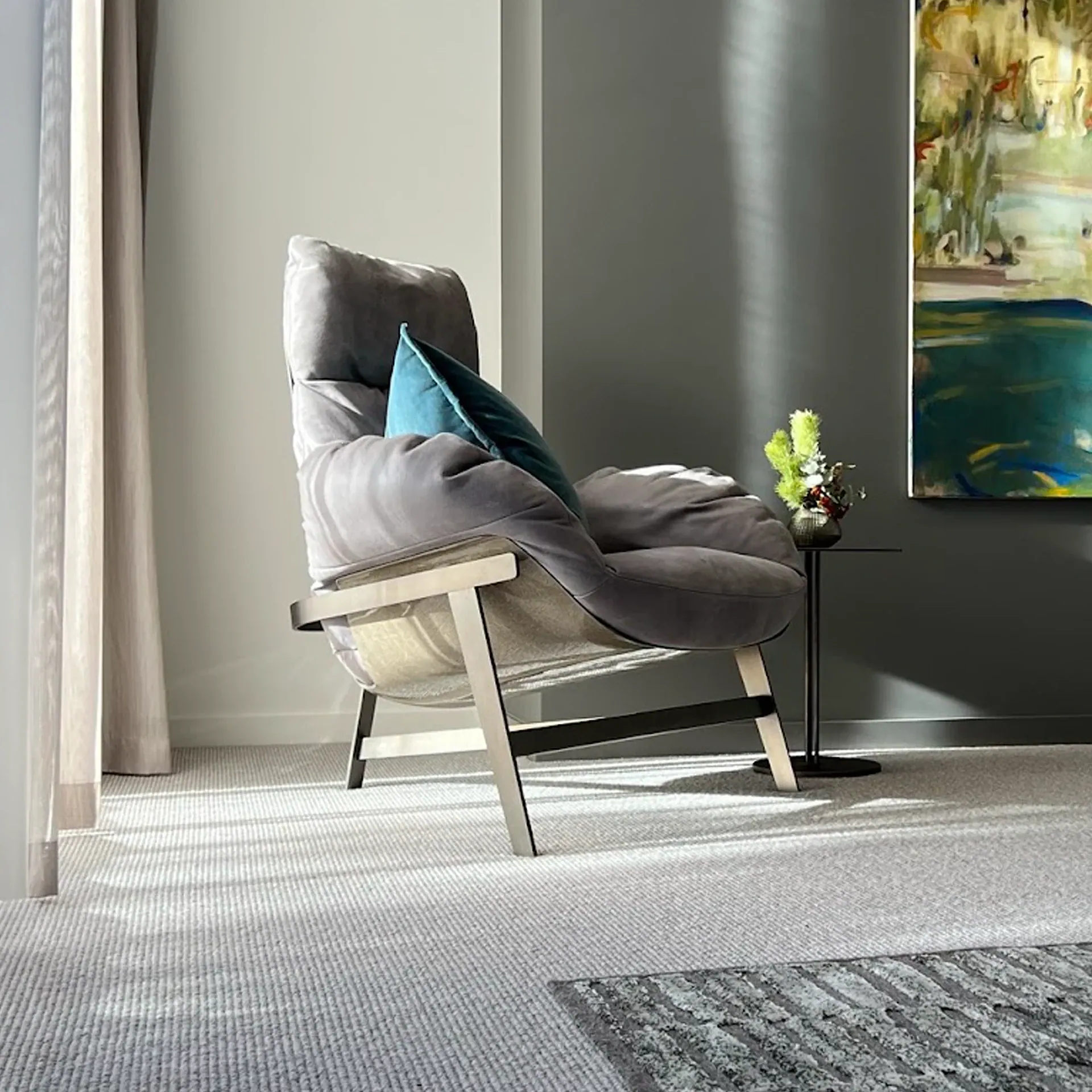 Sklar Furnishings Jupiter Sculptural Lounge Chair in gray fabric with teal cushion in living room.