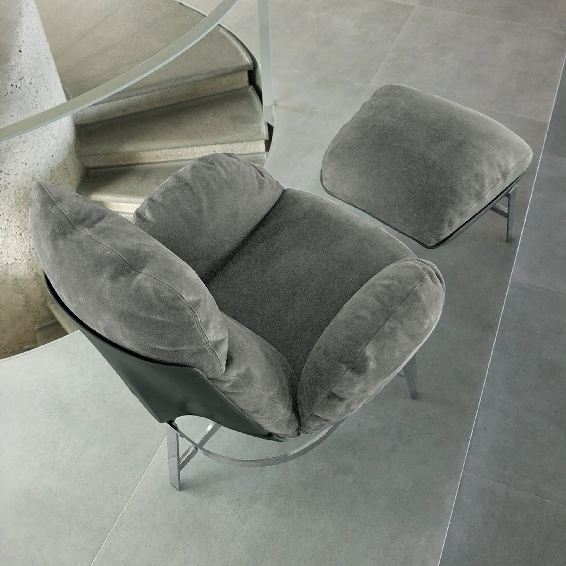 Sklar Furnishings grey lounge chair with matching ottoman in a modern interior.