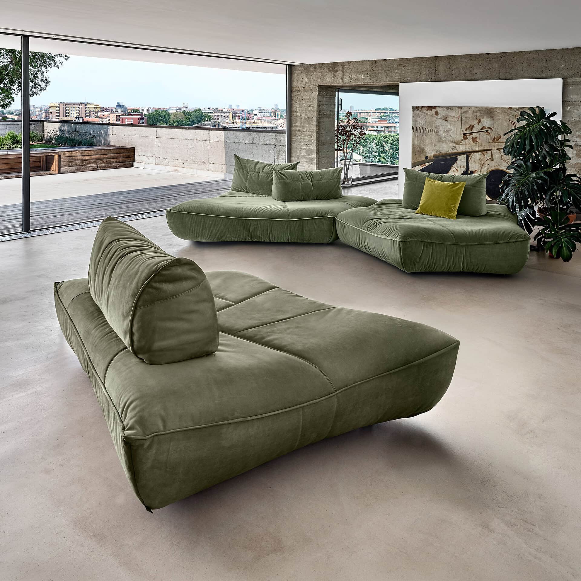 Modern green modular sofa in a spacious living room with city view.