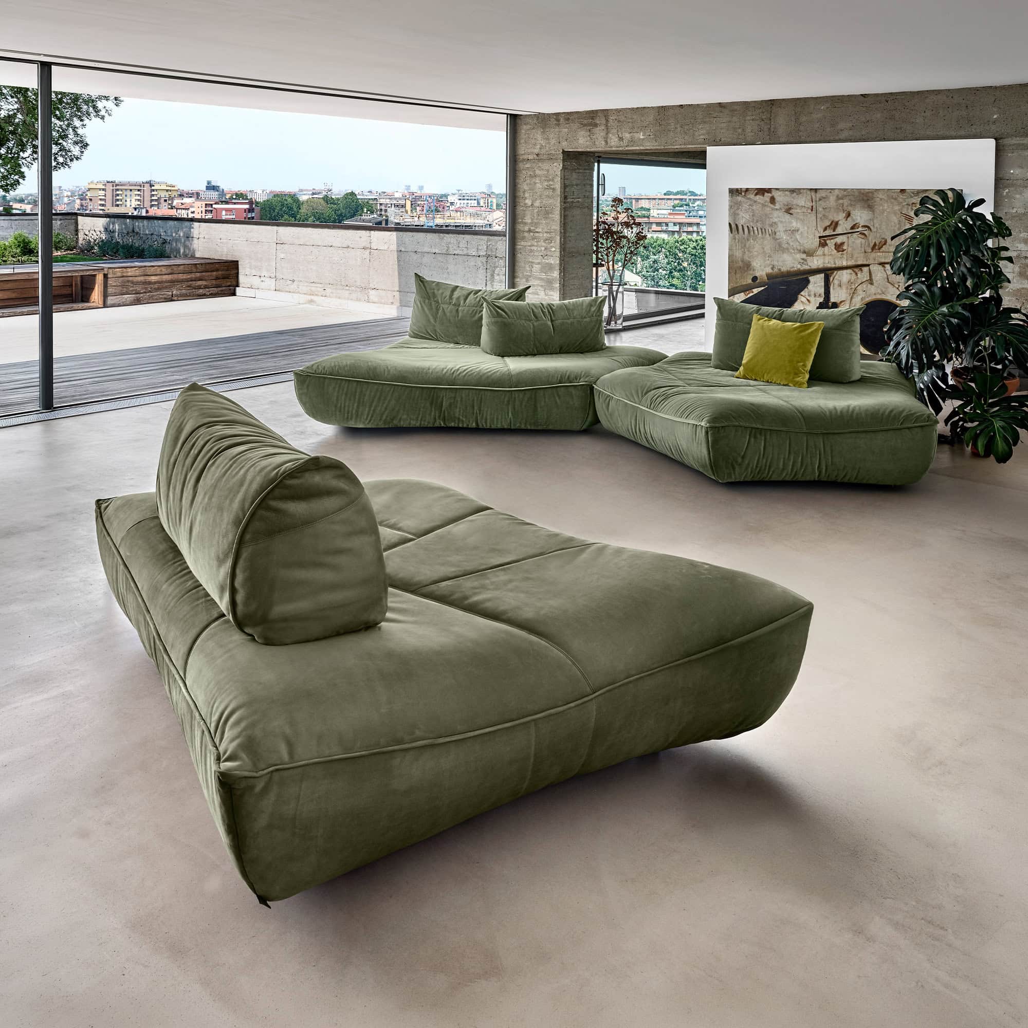 Modern green modular sofa in a spacious living room with city view.