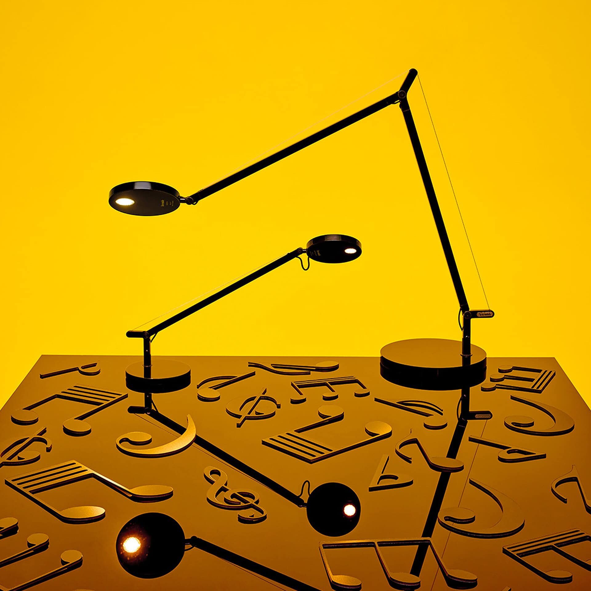 Adjustable Demetra table lamp with modern design on a yellow background.