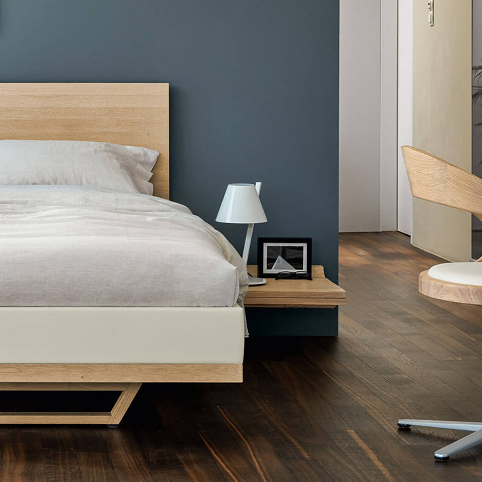 Modern bedroom with La Petite Table Lamp on nightstand, minimalist decor, dark wood flooring.