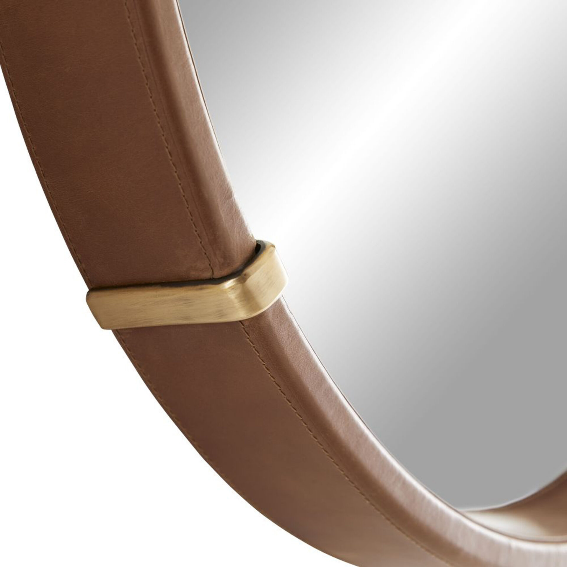 Close-up of a mirror with a curved brown leather frame and a brushed brass accent band.
