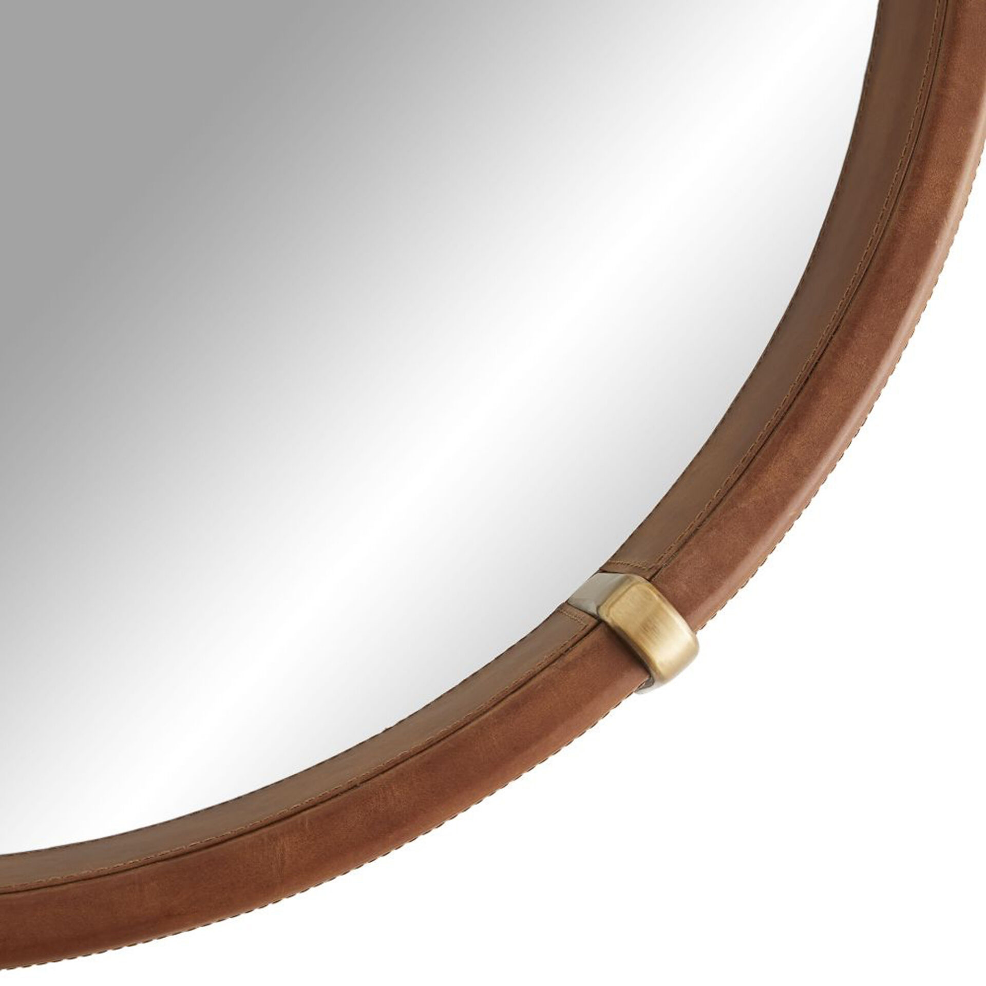 Close-up of a circular mirror with a brown leather frame and a brass accent on the top right.