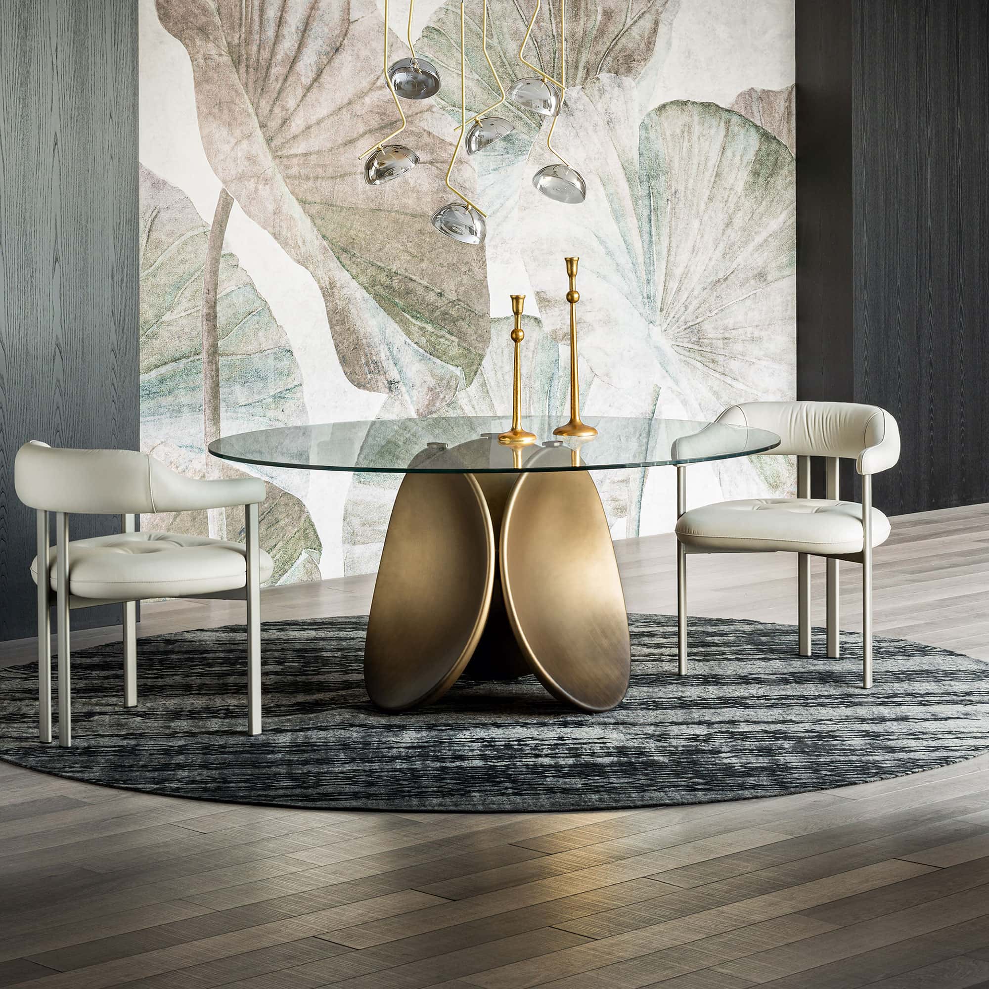 Modern round dining table with glass top and sculptural gold base in stylish dining room.