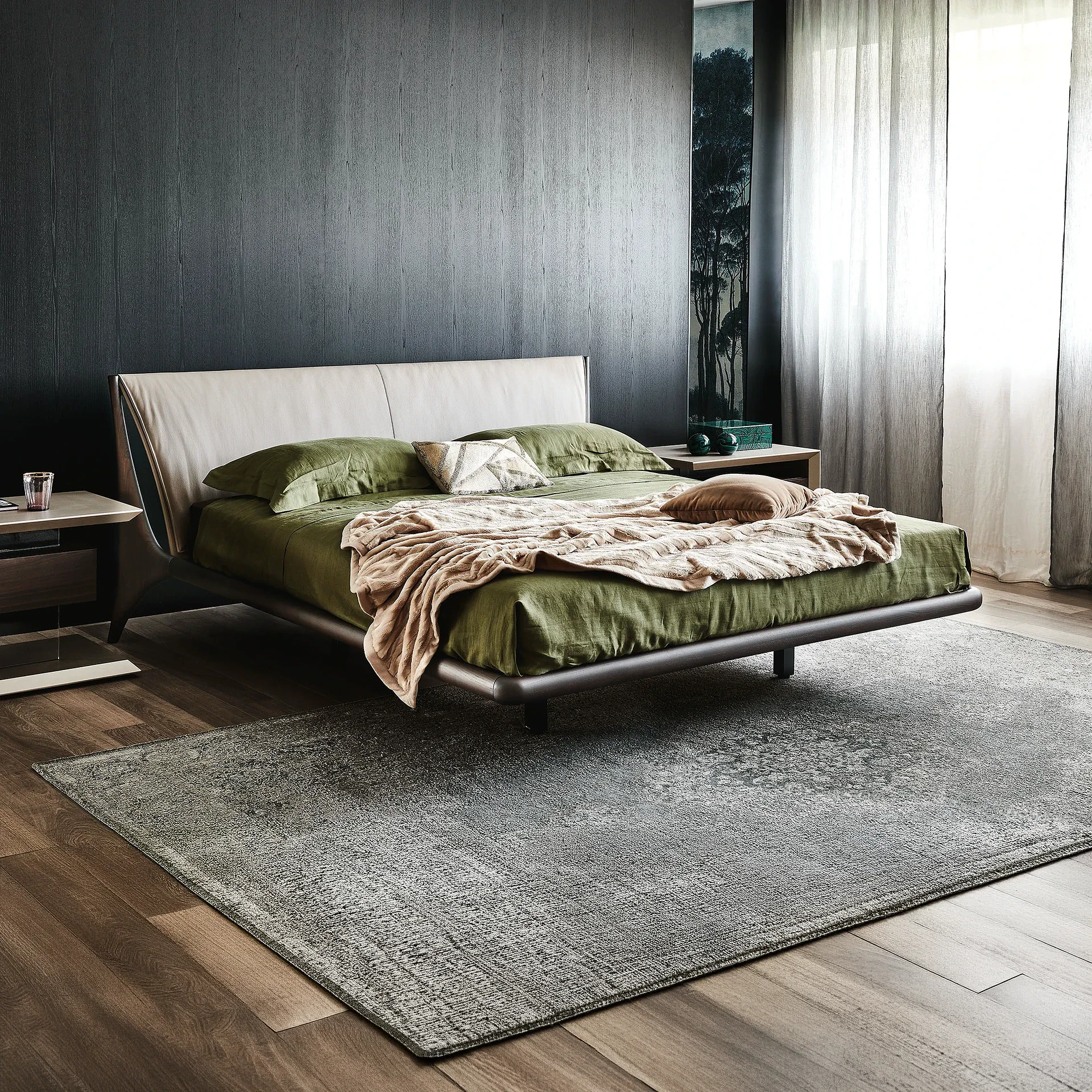 A modern bedroom with a beige upholstered bed, olive green bedding, dark wood nightstands, a dark textured wall, and sheer curtains.