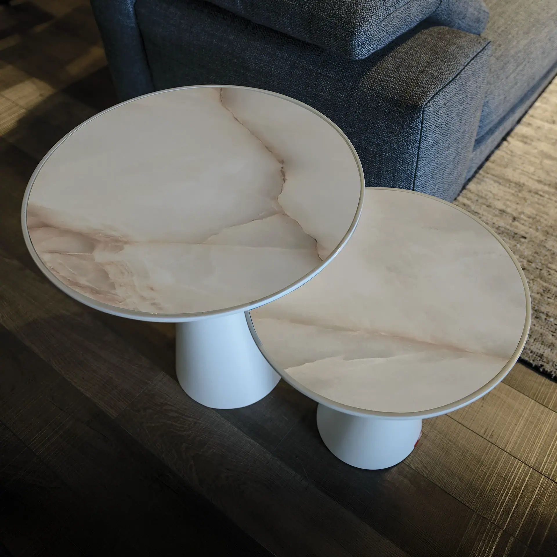 Sklar Furnishings marble end tables with white bases in living room.