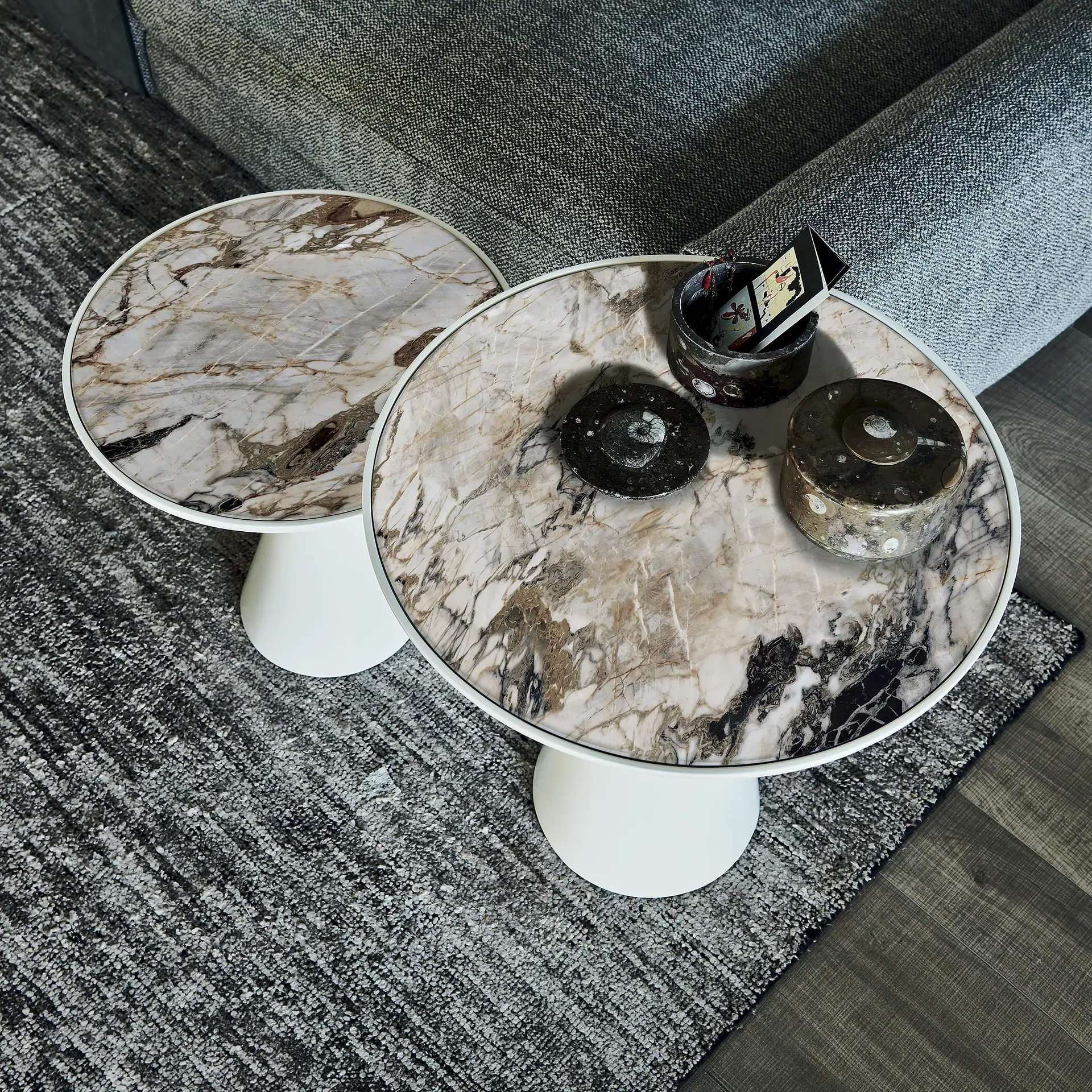 Sklar Furnishings marble end tables with white bases in a living room.