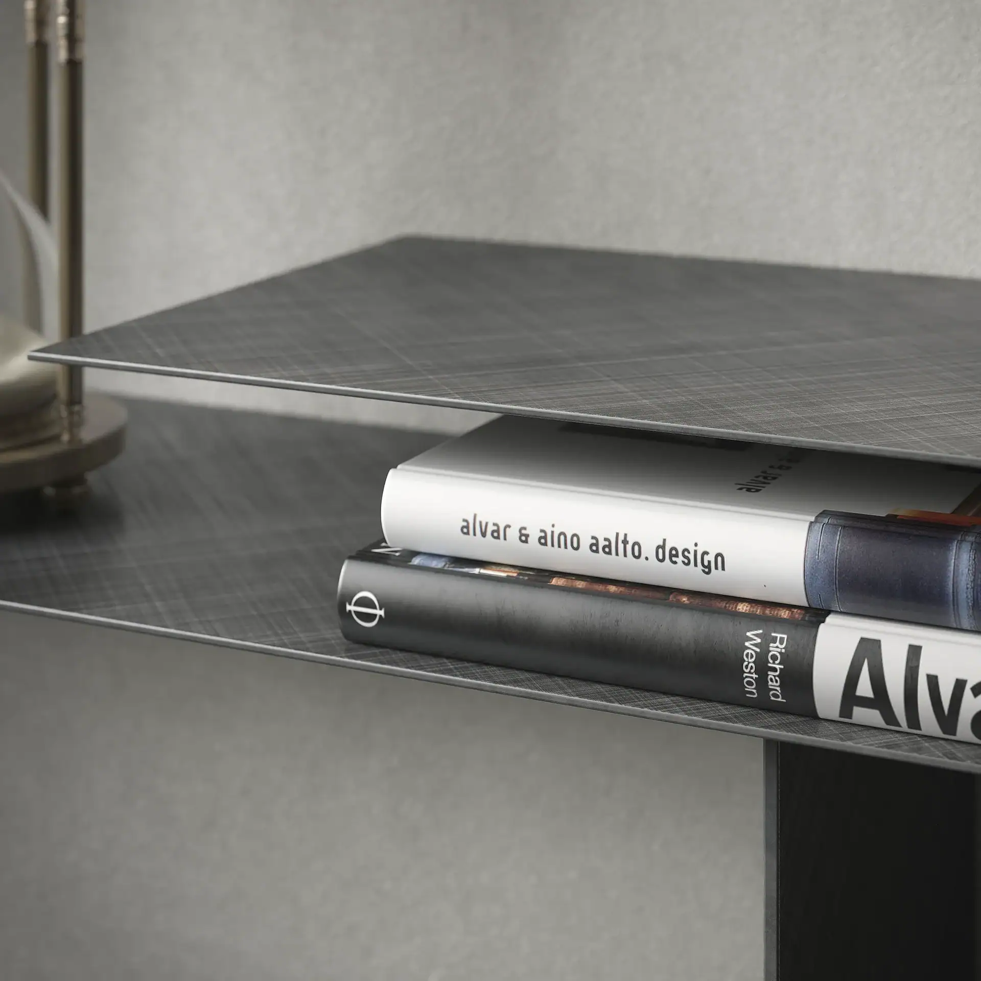 Two books, one white and one dark, stacked on a dark grey textured shelf.