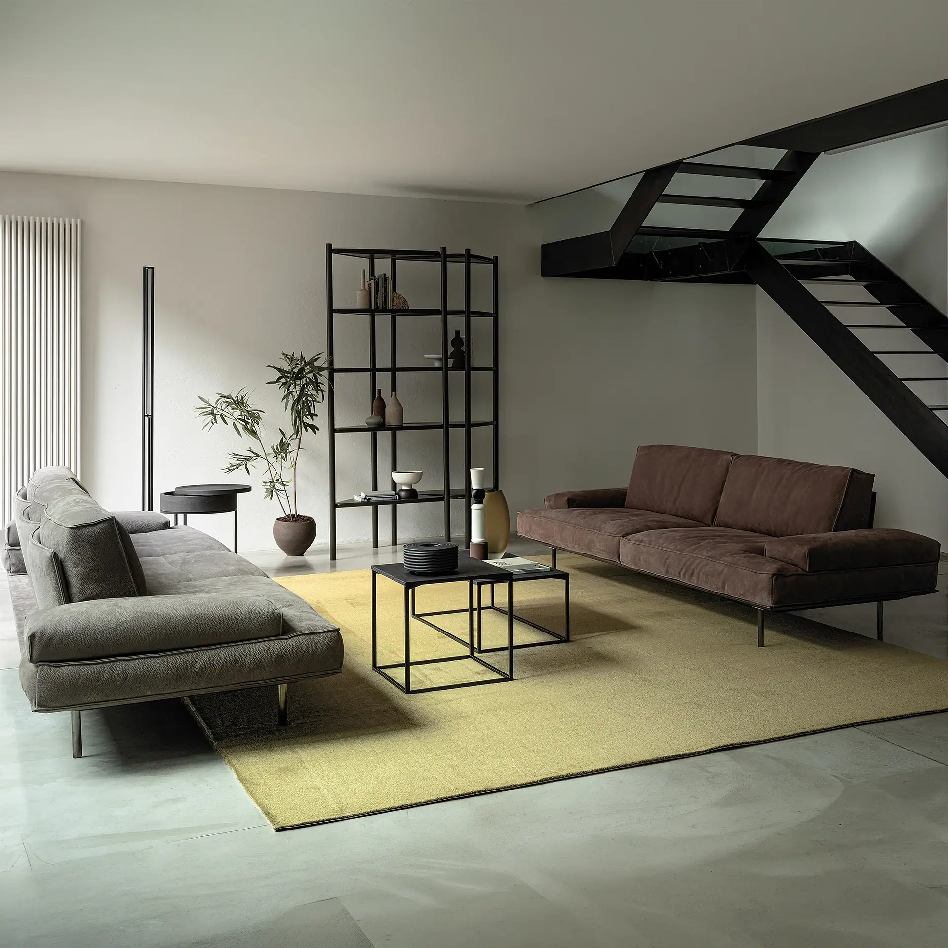 Modern living room with Vogue modular sofa, black staircase, and minimalist decor.