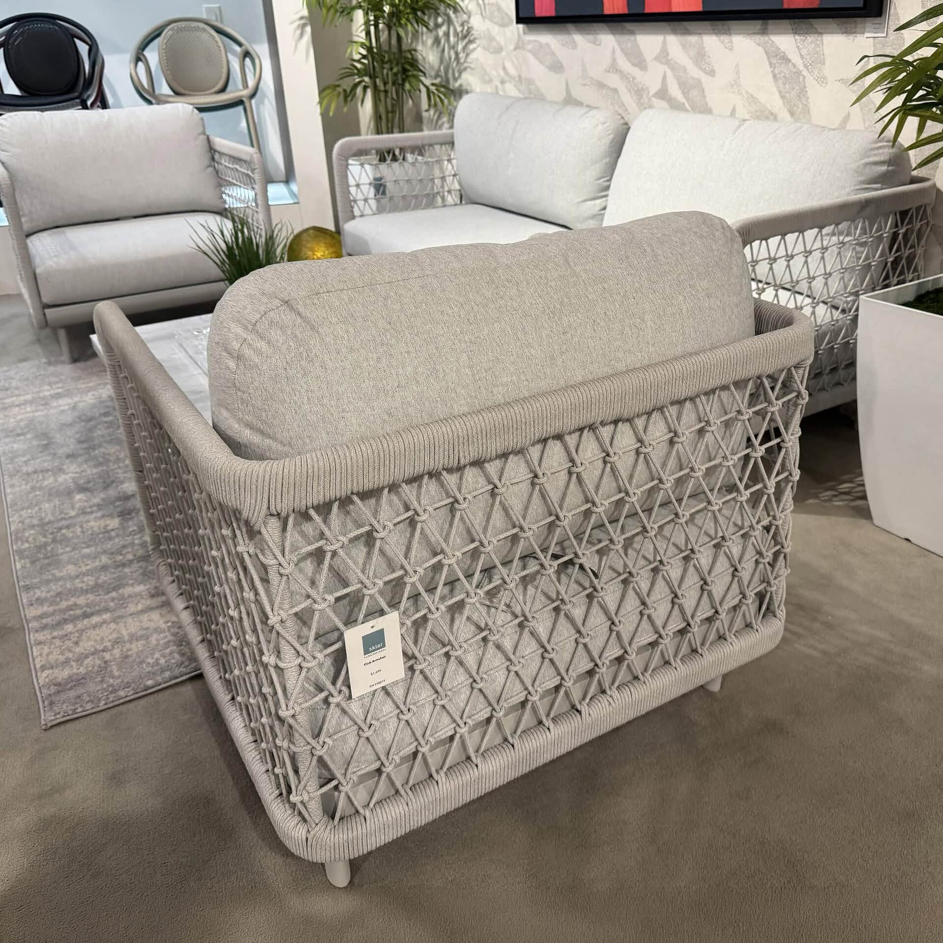 Outdoor armchair with woven rattan frame and plush cushion.
