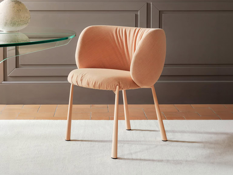 Elegant Midj Mys dining chair with soft peach upholstery and wooden legs.