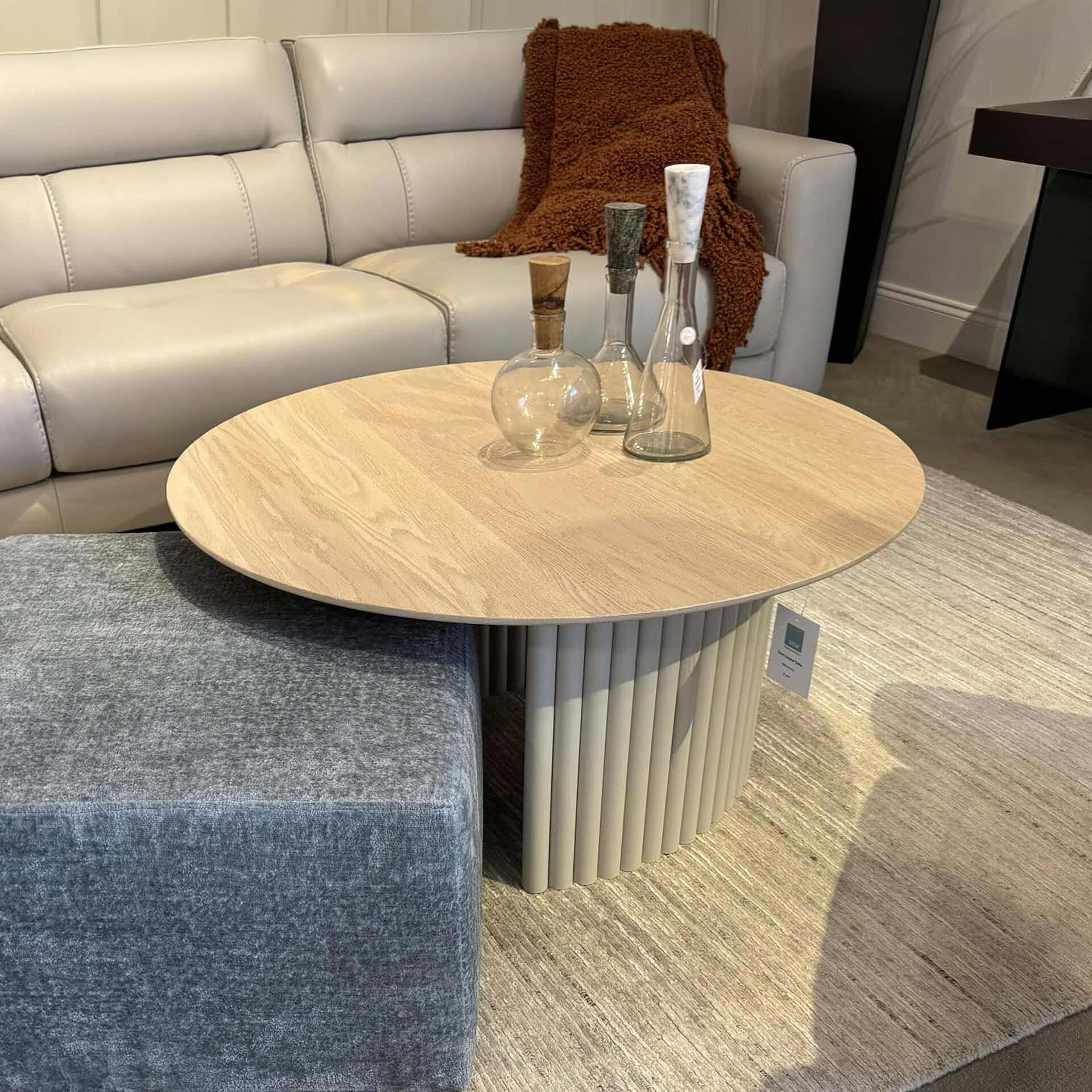 Modern round cocktail table with ribbed base in stylish living room setting.