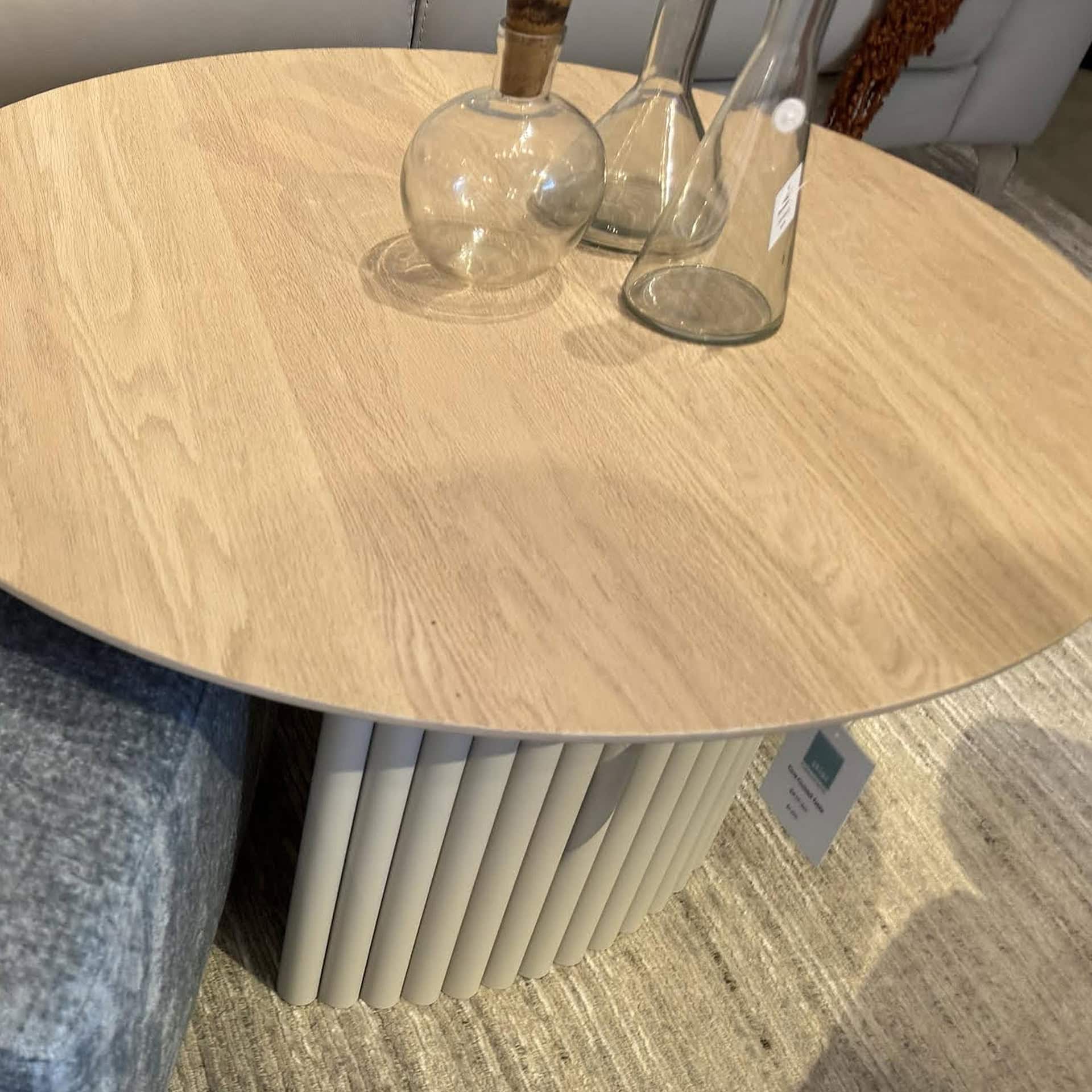 Modern round cocktail table with slatted base and wooden top.