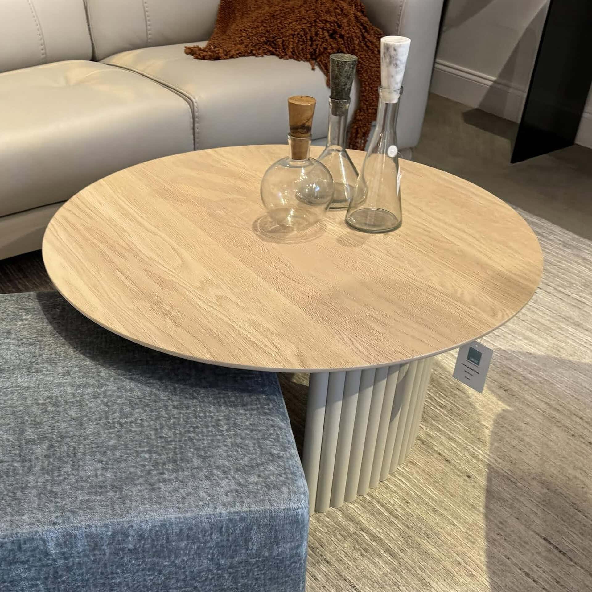 Modern round wooden cocktail table with unique base design.