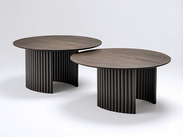 Modern Trica Cove round cocktail table with ribbed black base and wooden top.