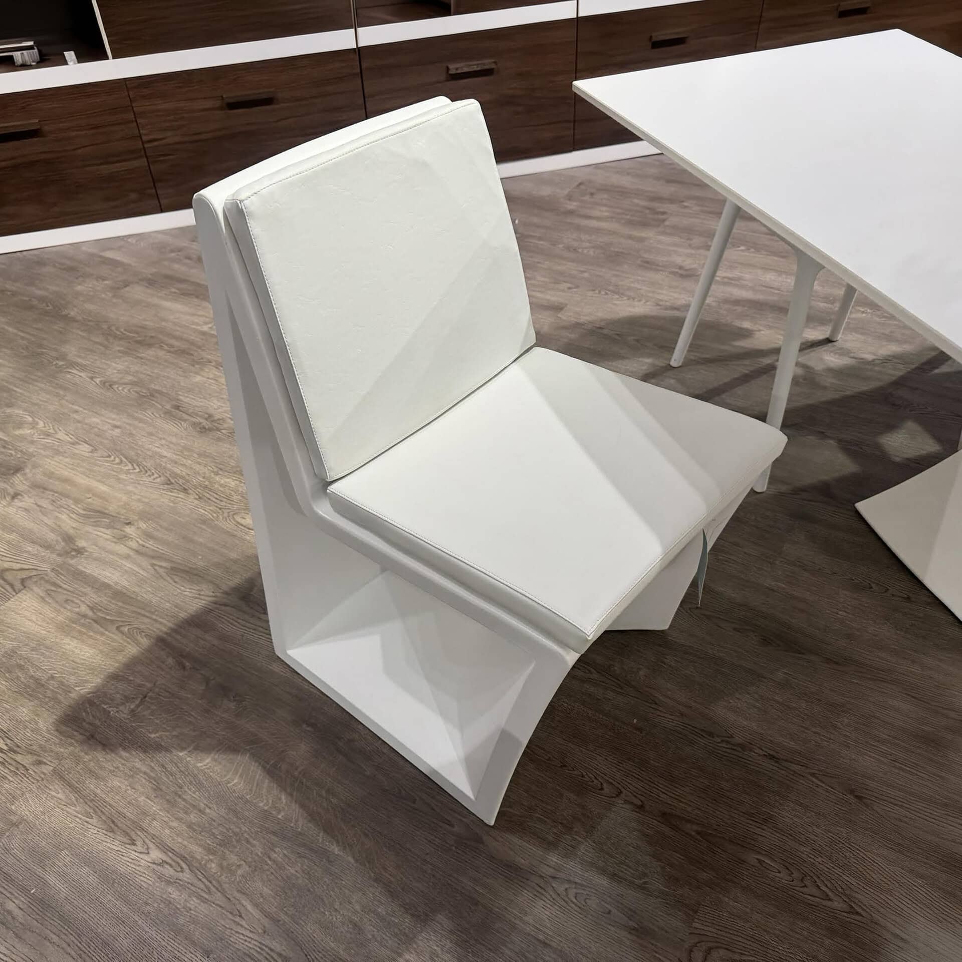 Contemporary white upholstered dining chair with sleek design.