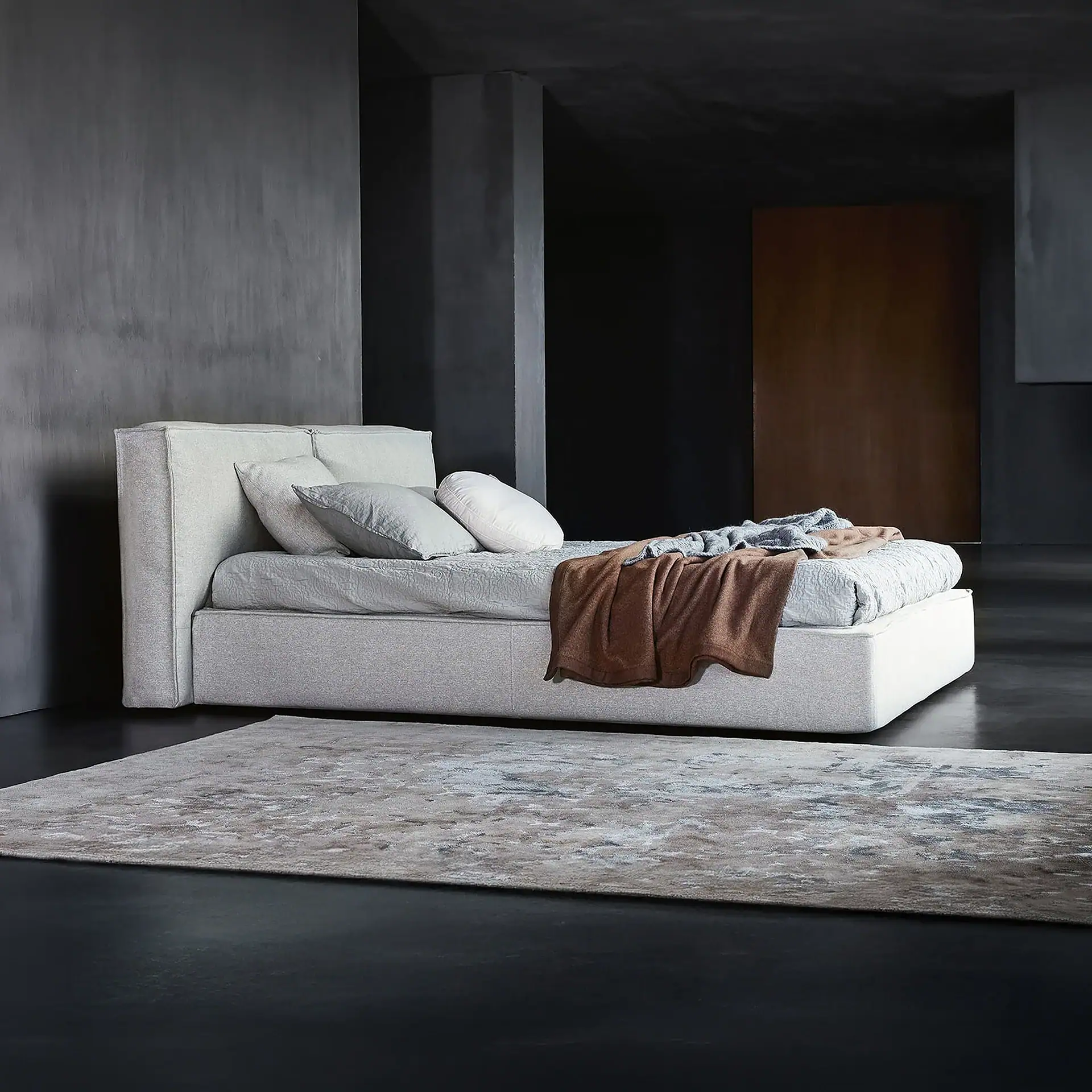 Elegant upholstered bed with neutral bedding in a sleek, modern bedroom.