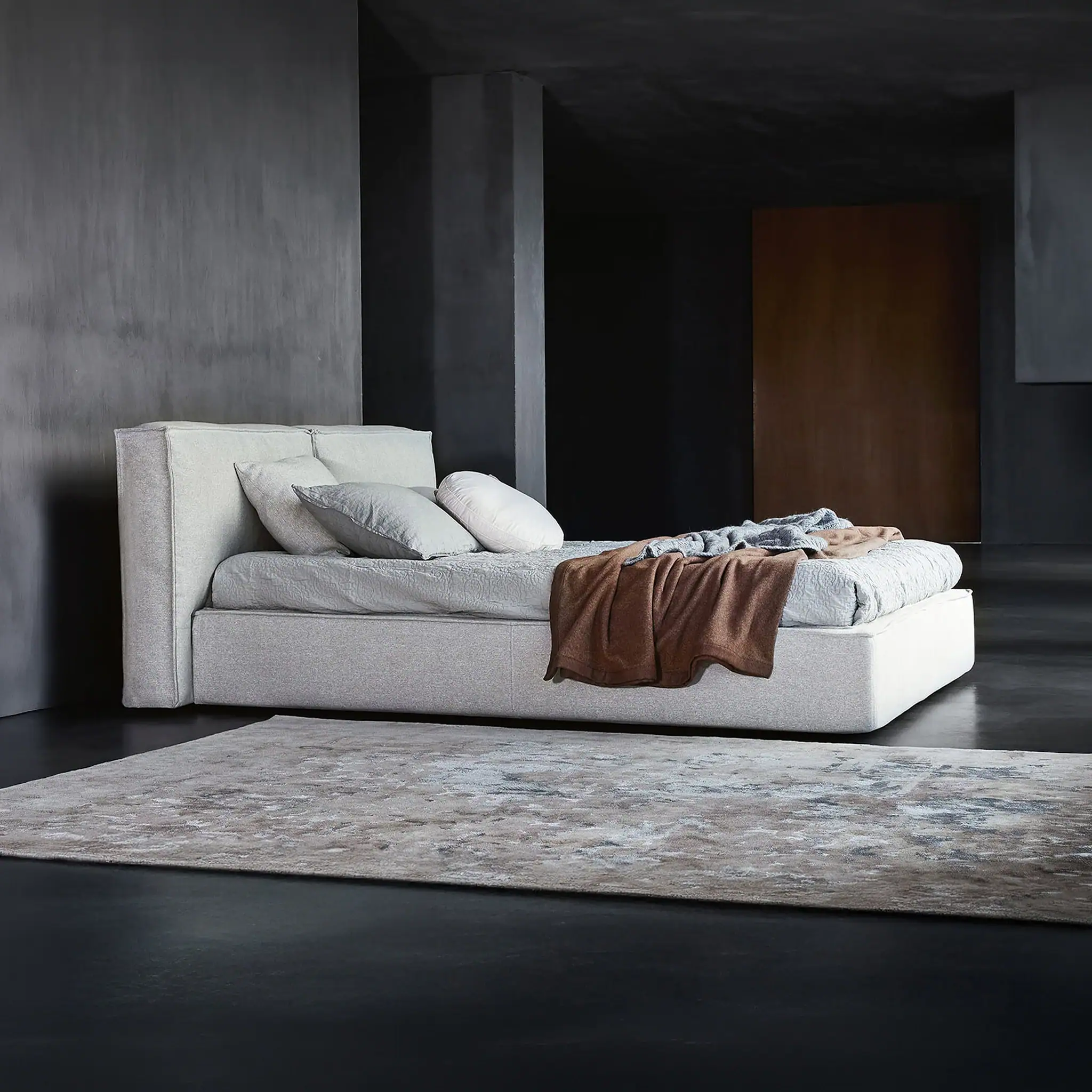 Elegant upholstered bed with neutral bedding in a sleek, modern bedroom.
