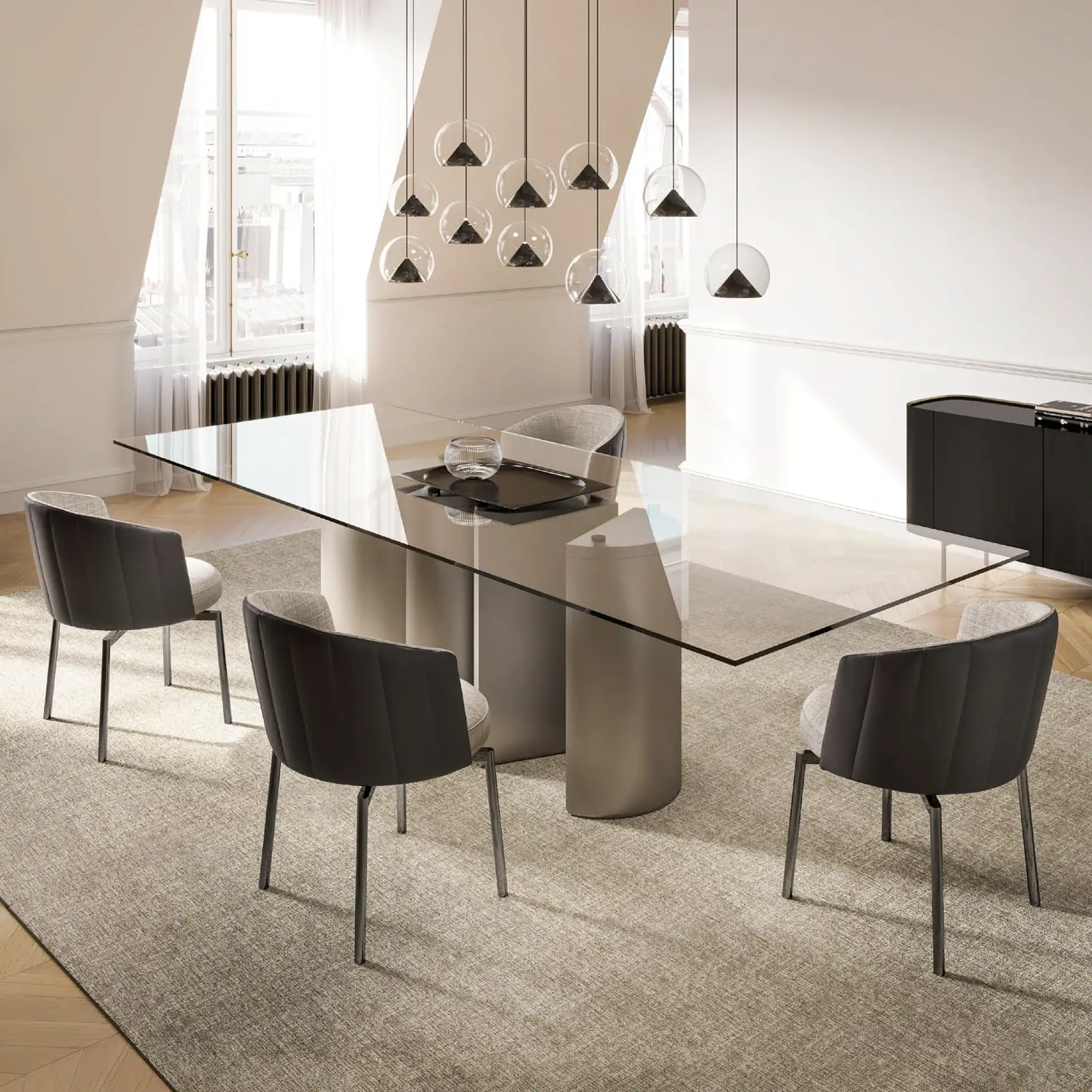 A modern dining room with a glass table, four dark and light grey chairs, and a cluster of spherical pendant lights.