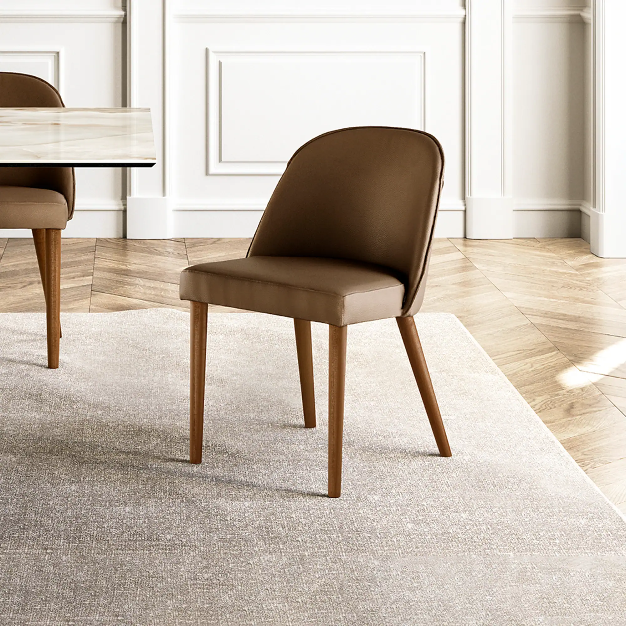 A brown upholstered dining chair with wooden legs sits on a light beige rug in a room with a marble table and white paneled walls.