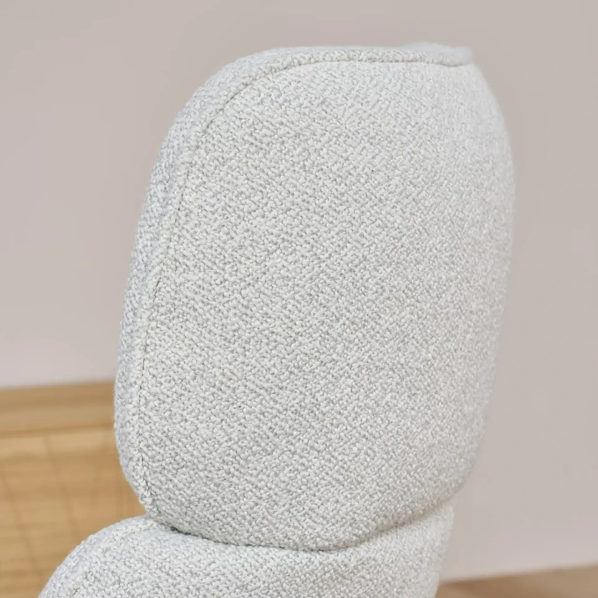 Close-up of a light gray textured upholstered chair backrest and a small part of the seat.