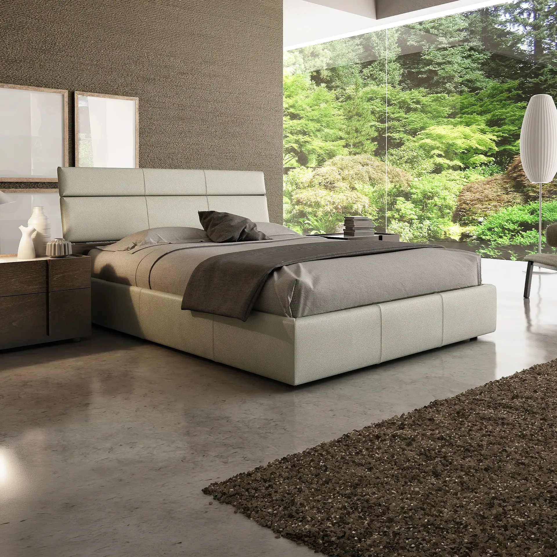 A modern bedroom with a light gray upholstered bed, dark brown nightstand, and a large window showcasing a view of green trees. A dark brown rug is on the concrete floor.