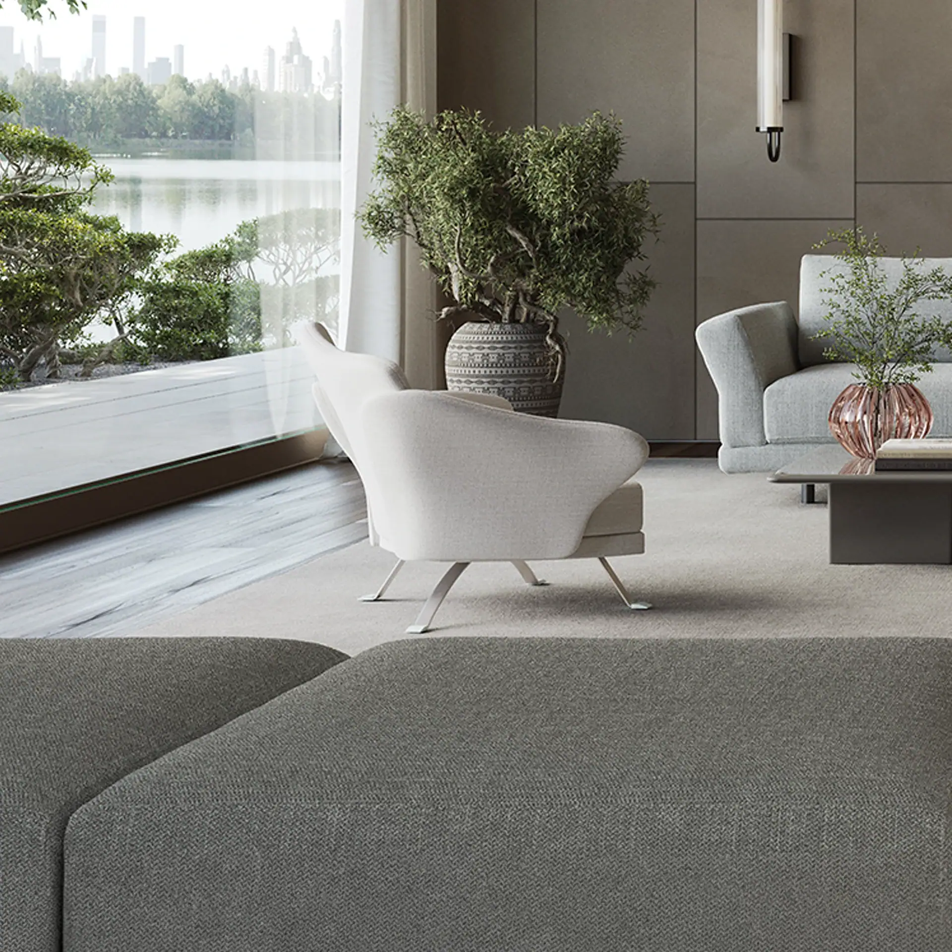 A modern living room with a large window overlooking a lake, trees, and a city skyline. A cream armchair, gray sofa, and potted plants are visible.