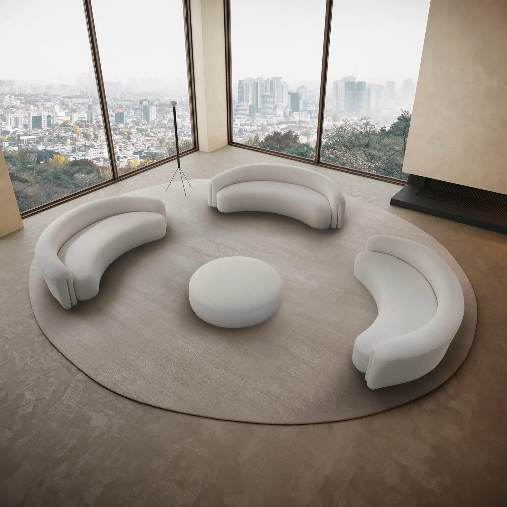 A modern living room with three curved white sofas and a round ottoman on a circular rug, facing large windows with a panoramic city view.