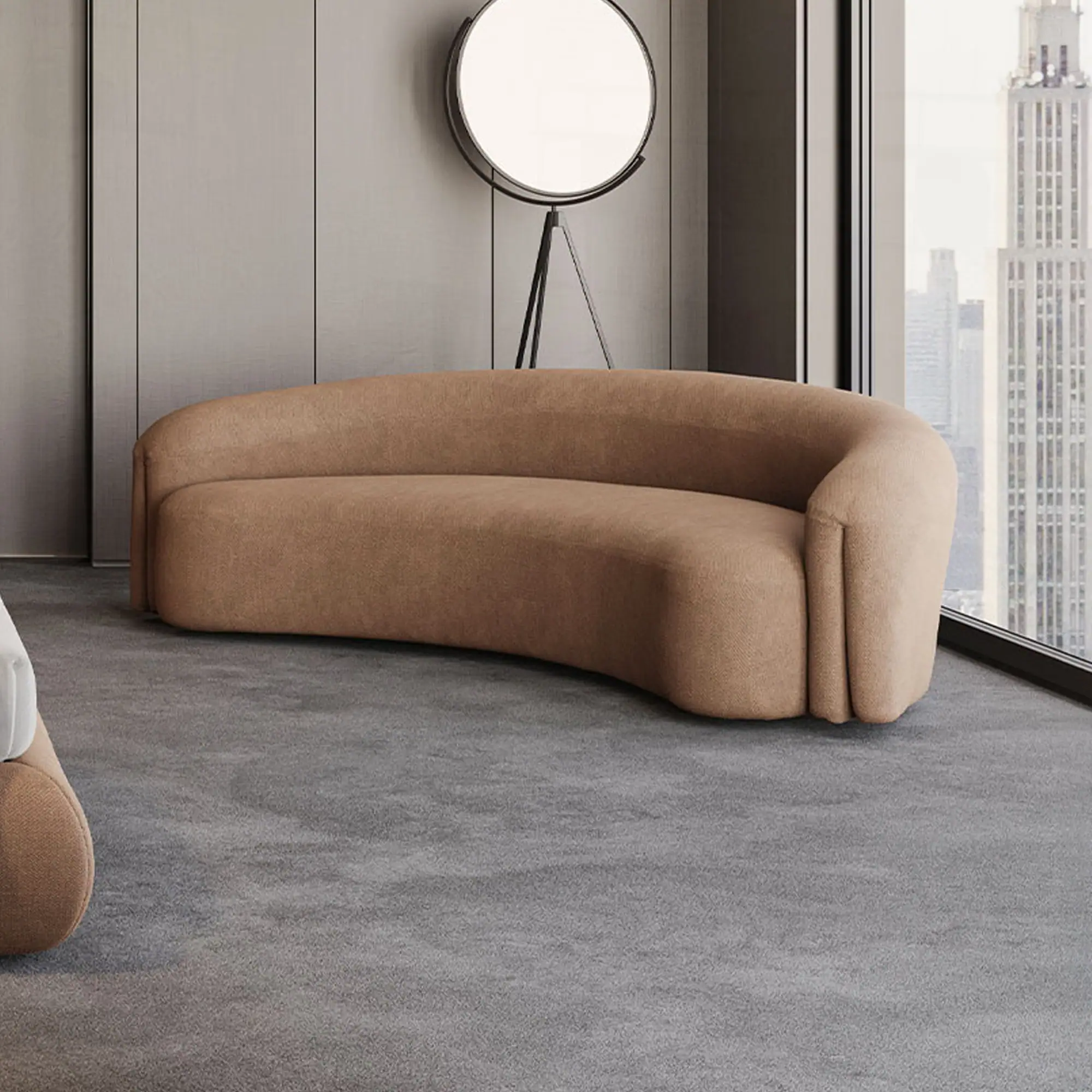 A modern living room with a curved tan sofa, a black circular floor lamp, and a large window overlooking a city skyline.