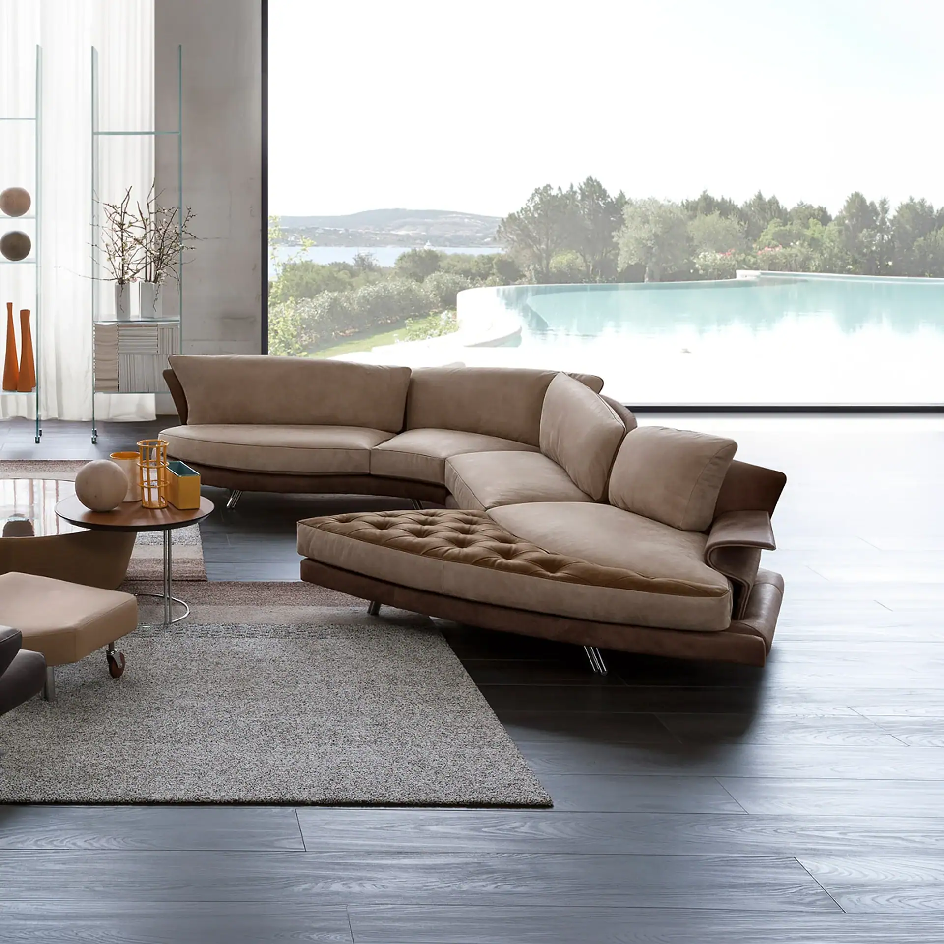 A luxurious modern living room with a large Super Roy Modular Curved Sofa, a glass coffee table, and a large window overlooking an infinity pool, trees, and a body of water.