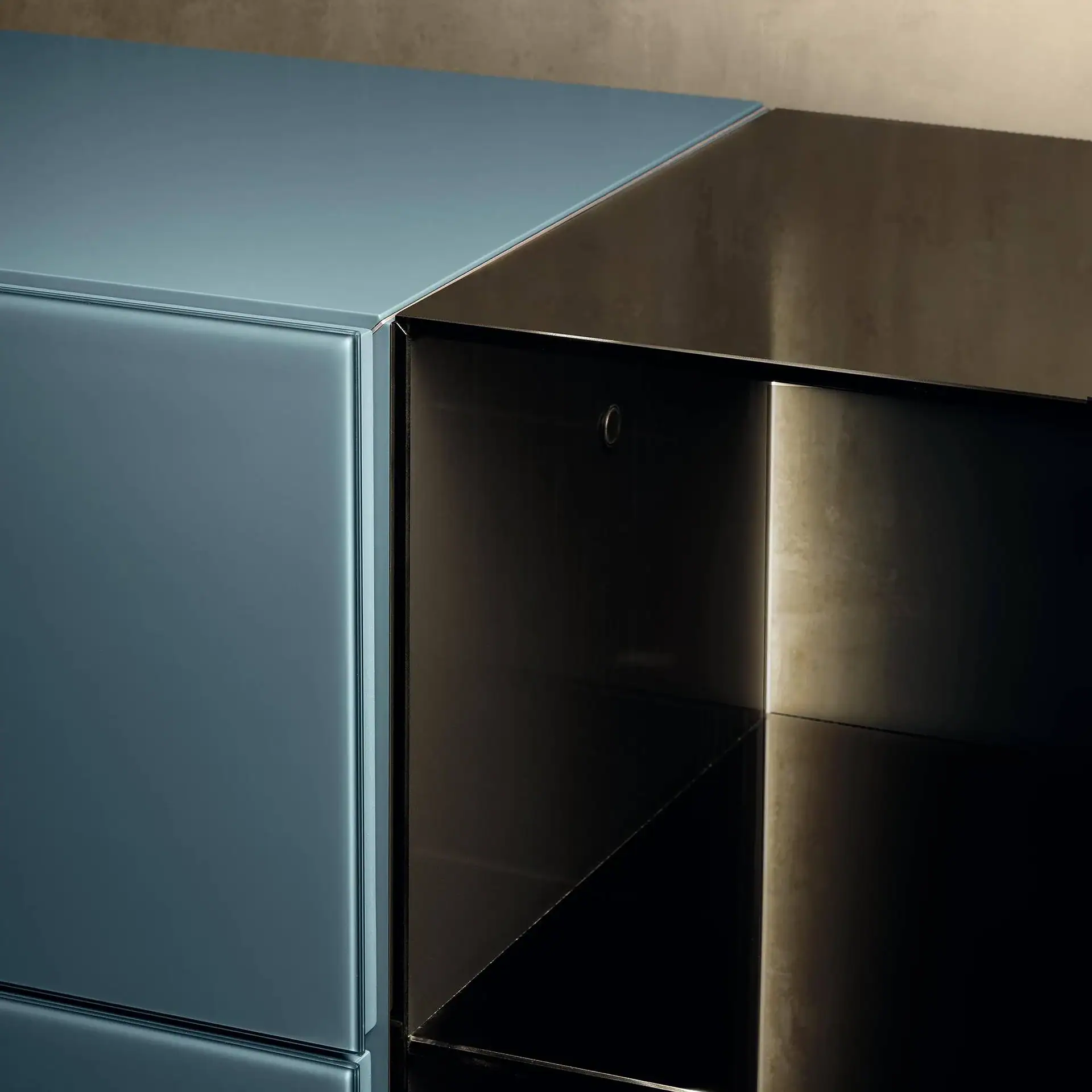 Close-up of modern furniture: a light blue-grey glossy panel next to a dark, open unit with an illuminated interior.