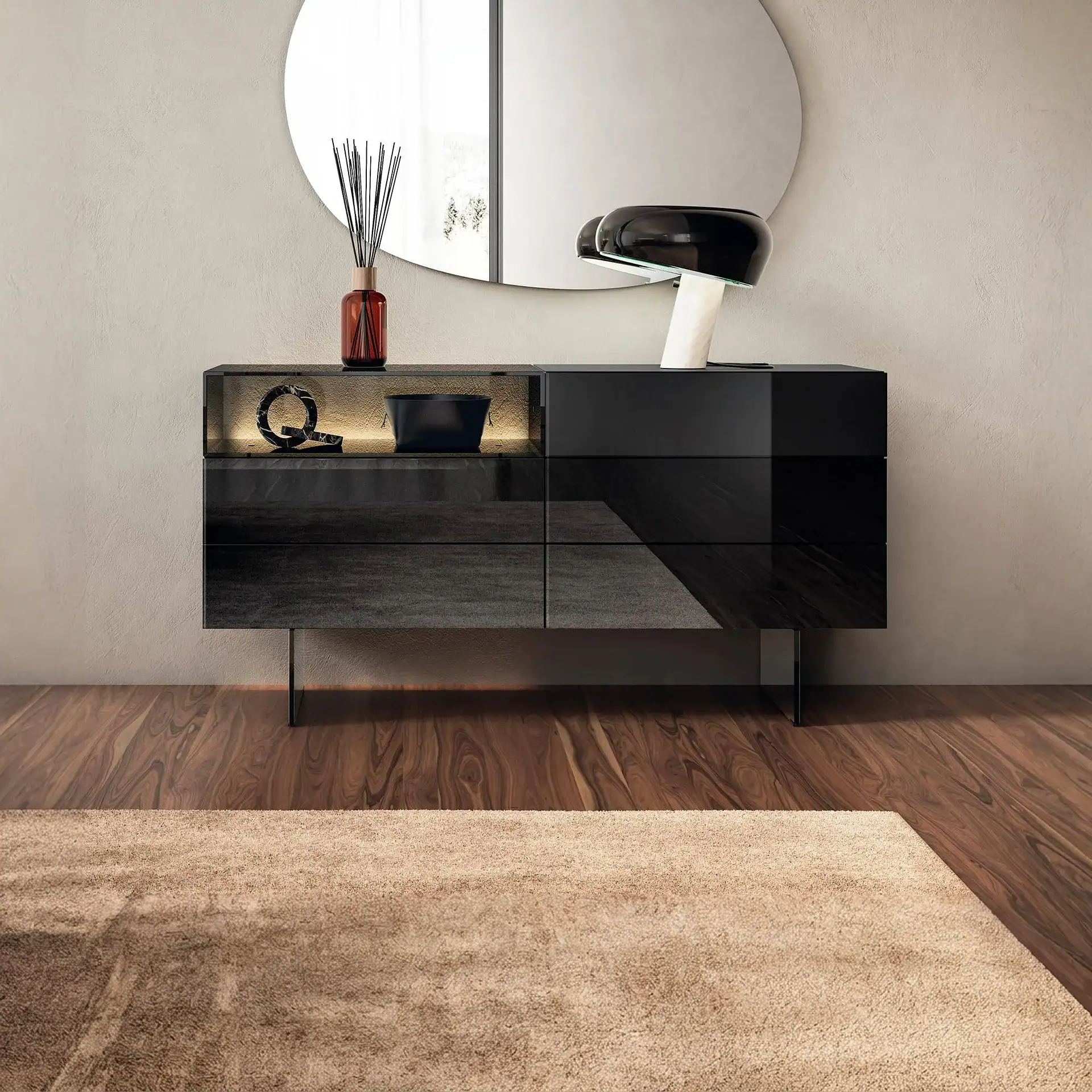 A modern dark wood and glass sideboard with a round mirror, a diffuser, a decorative 'Q' object, a black bowl, and a mushroom lamp, set against a beige wall and wooden floor with a light brown shag rug.