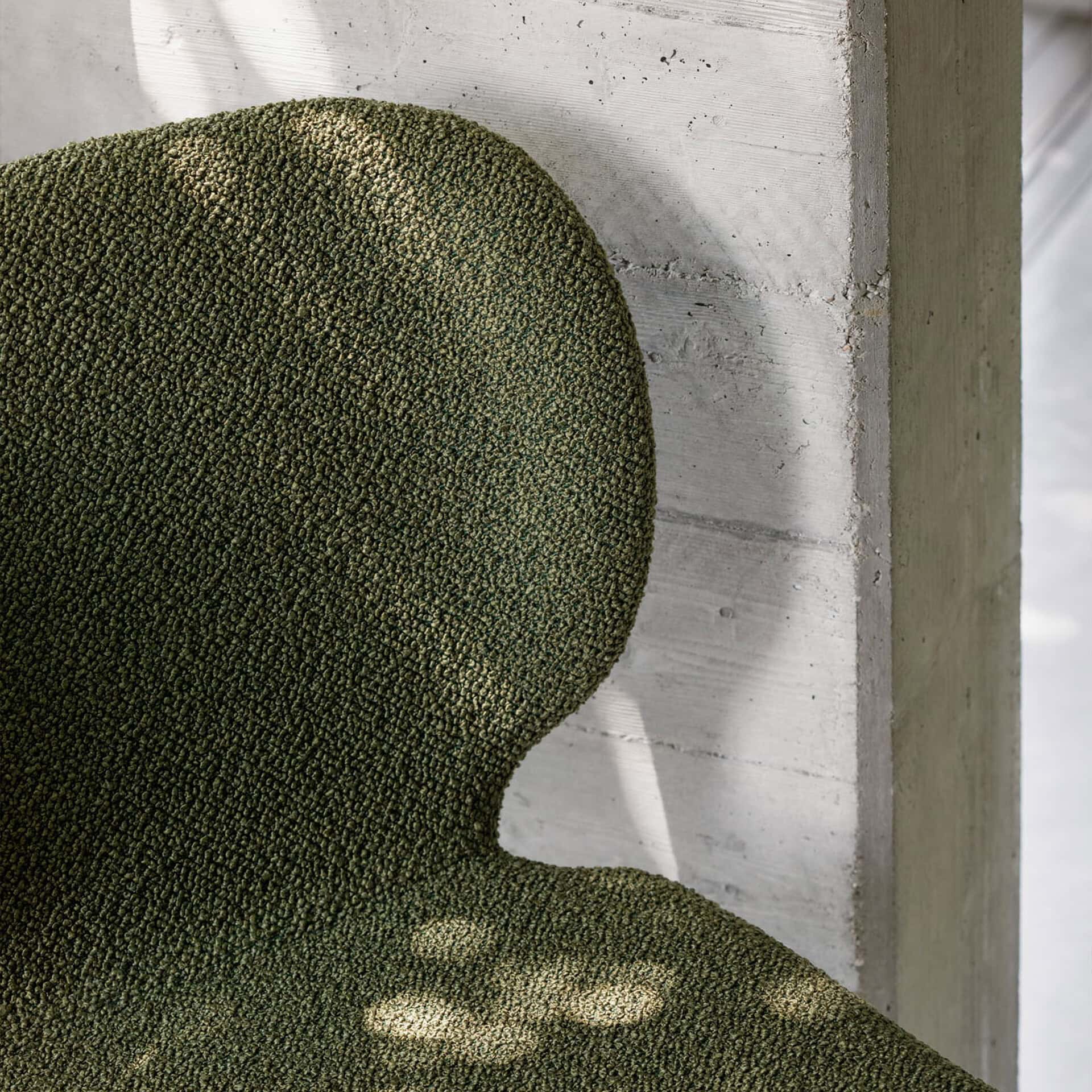 Upholstered wrap dining chair with textured green fabric.