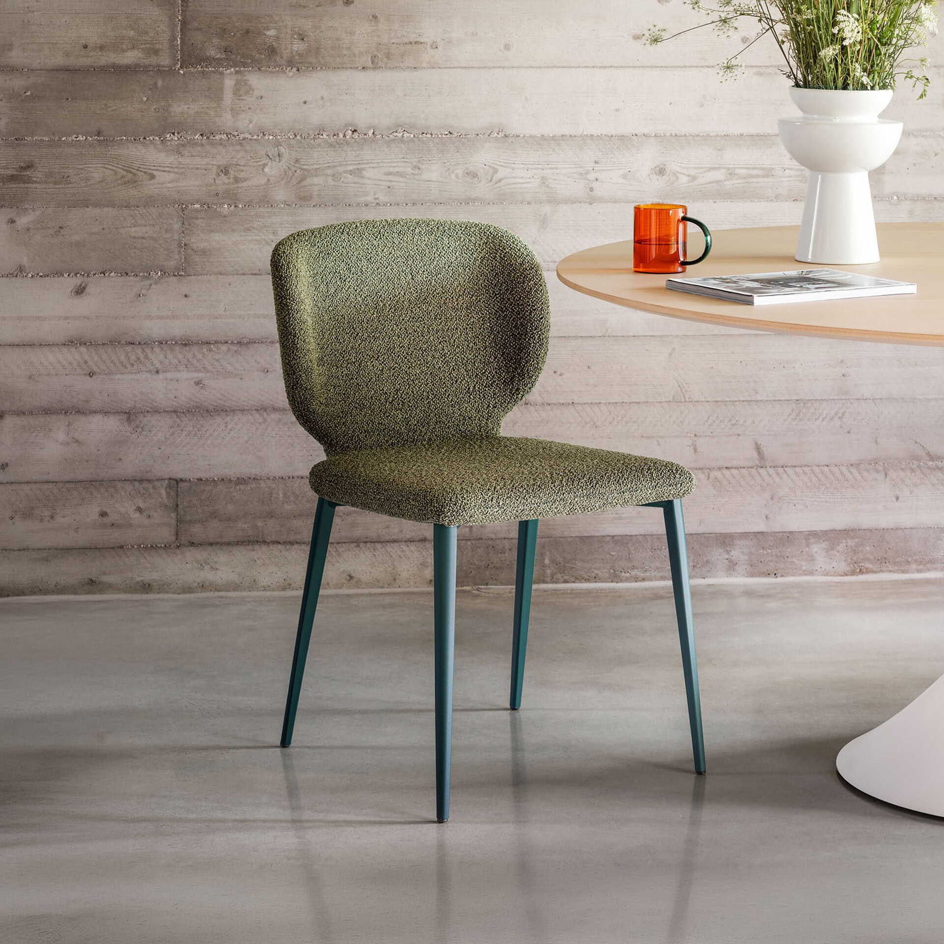 Upholstered dining chair with green fabric and sleek blue legs, ideal for modern dining spaces.